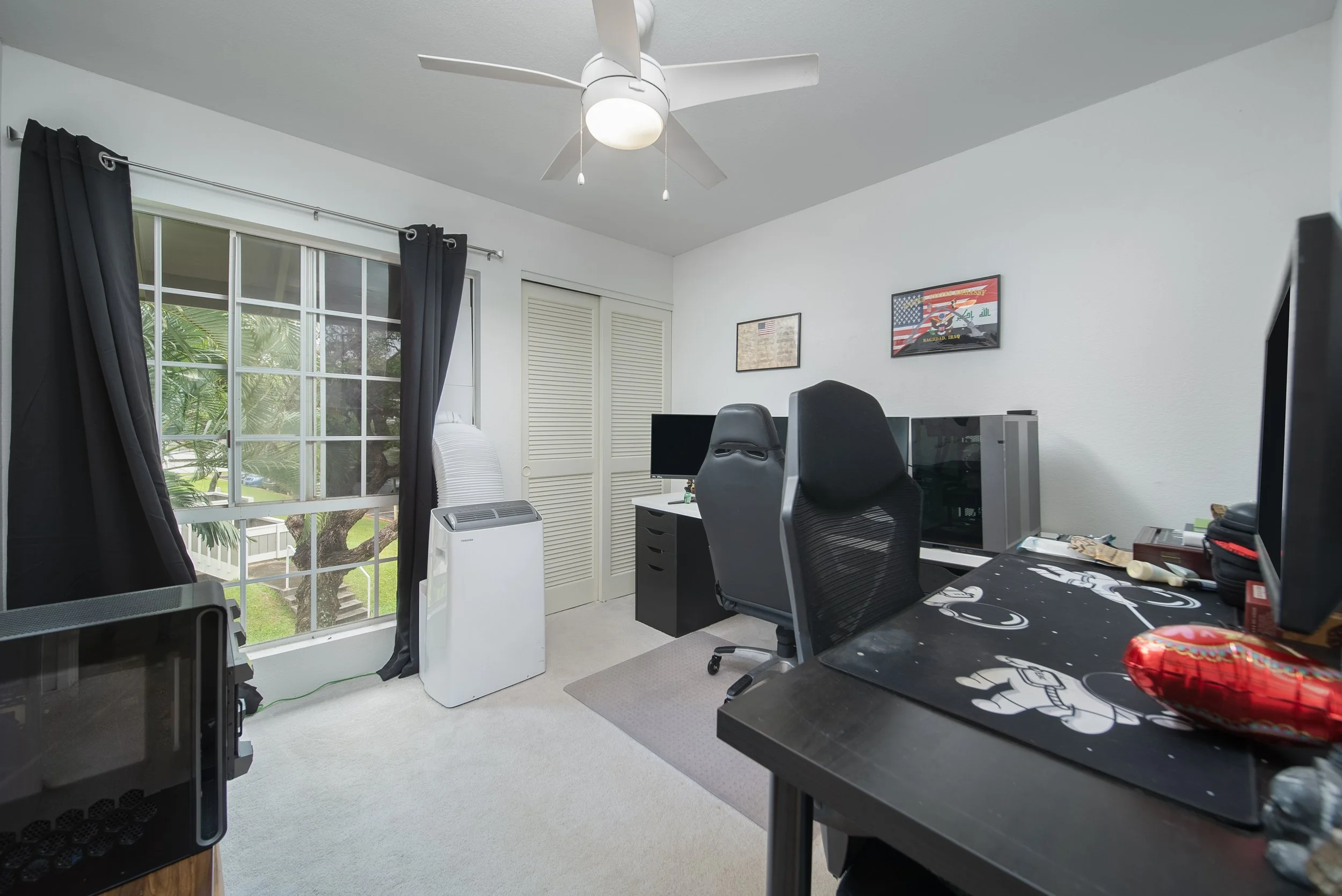 Second bedroom set up as a home office with window and closet