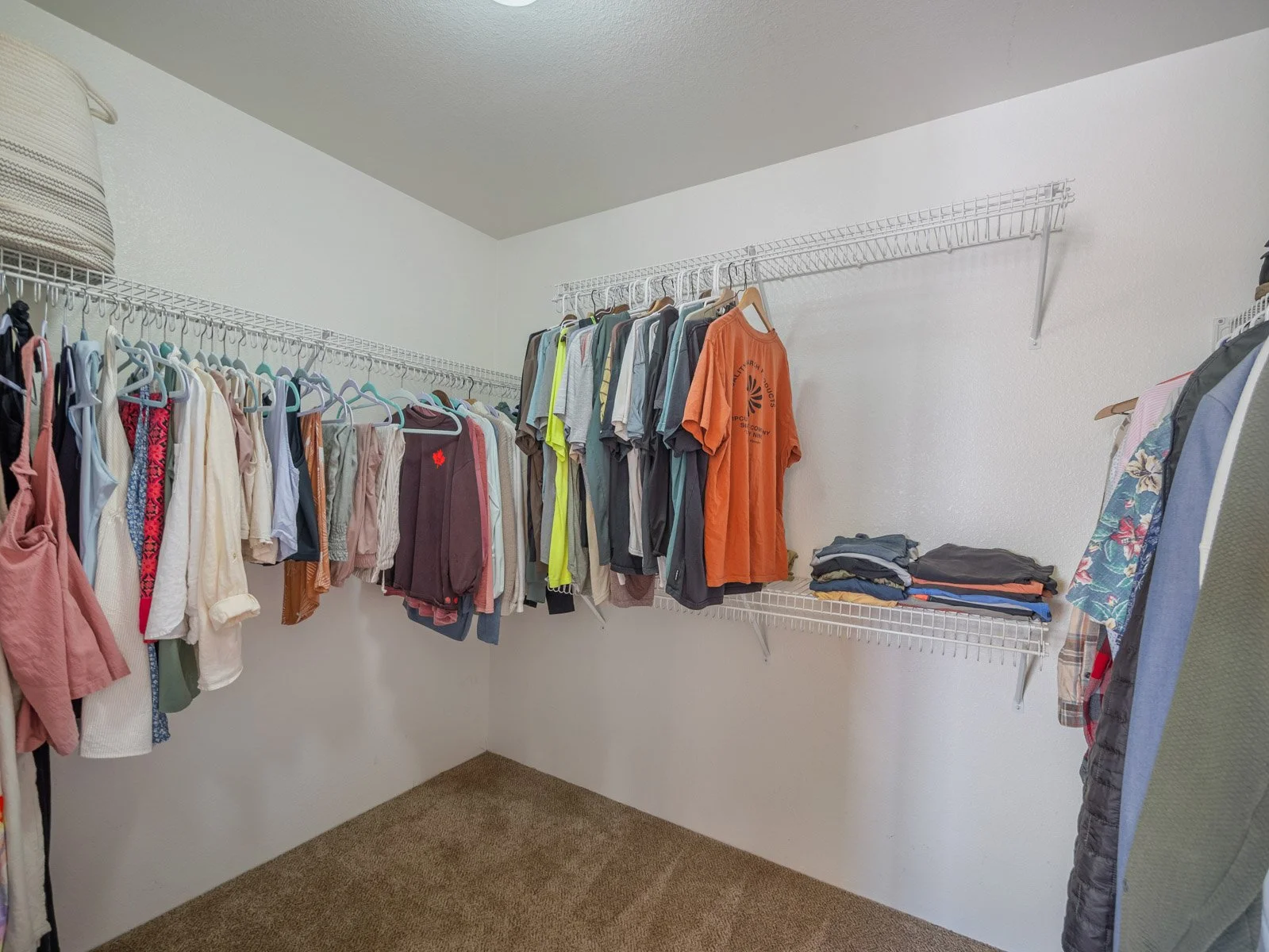 Walk in closet with hanging rods, wire shelving and carpet