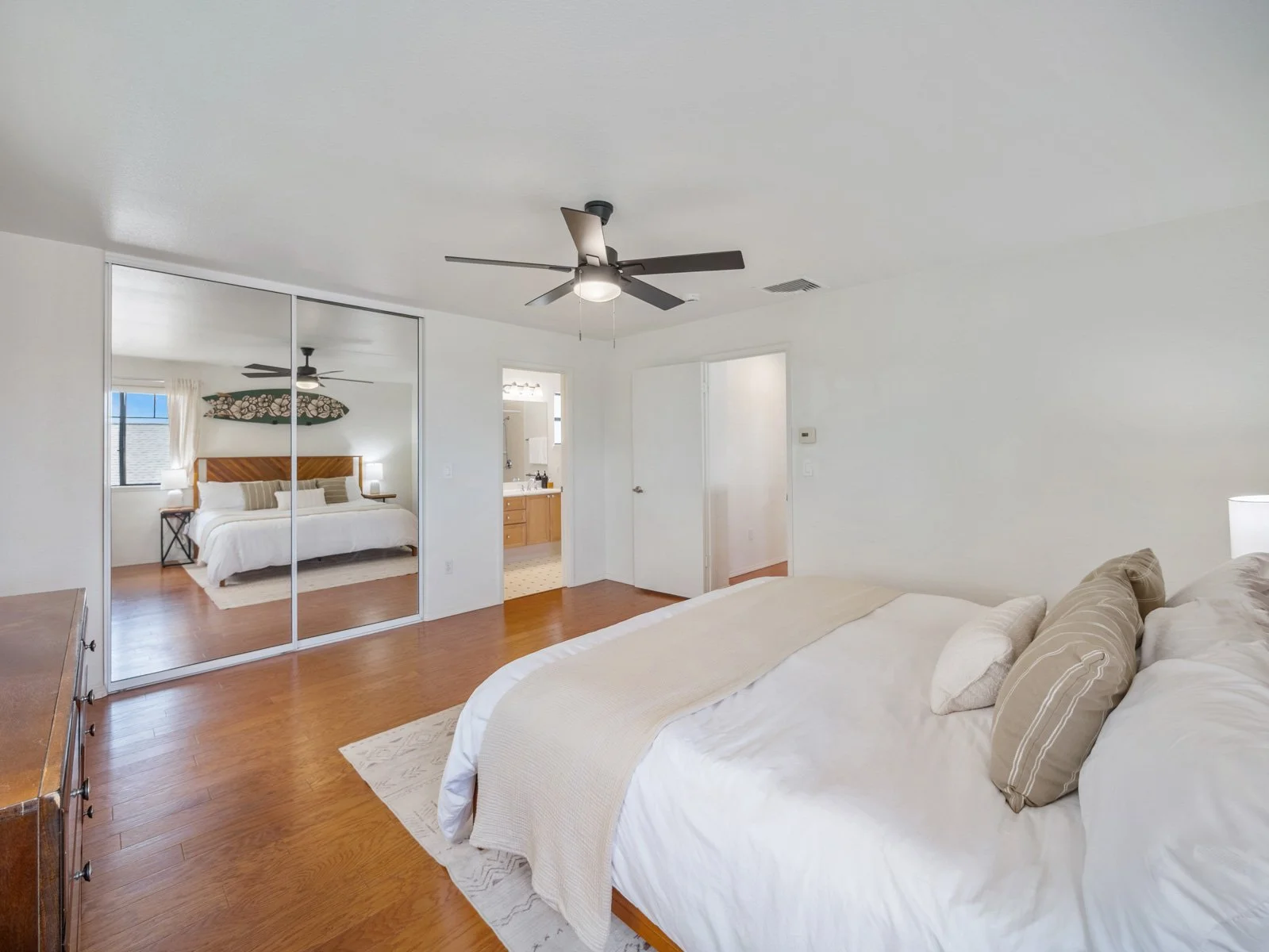 Primary bedroom with mirrored closet doors and ensuite bathroom beyond