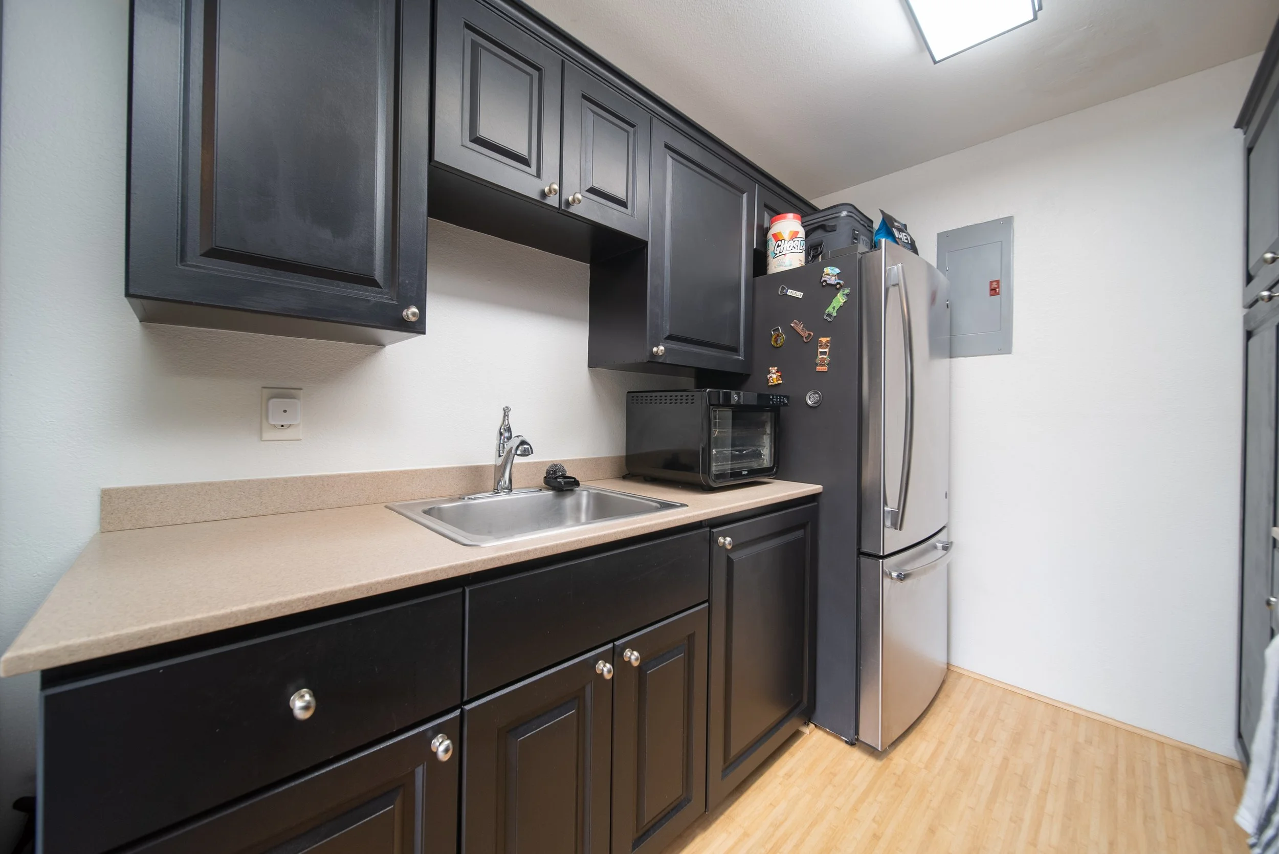 Kitchen with stainless refrigerator, sink and dark cabinetry