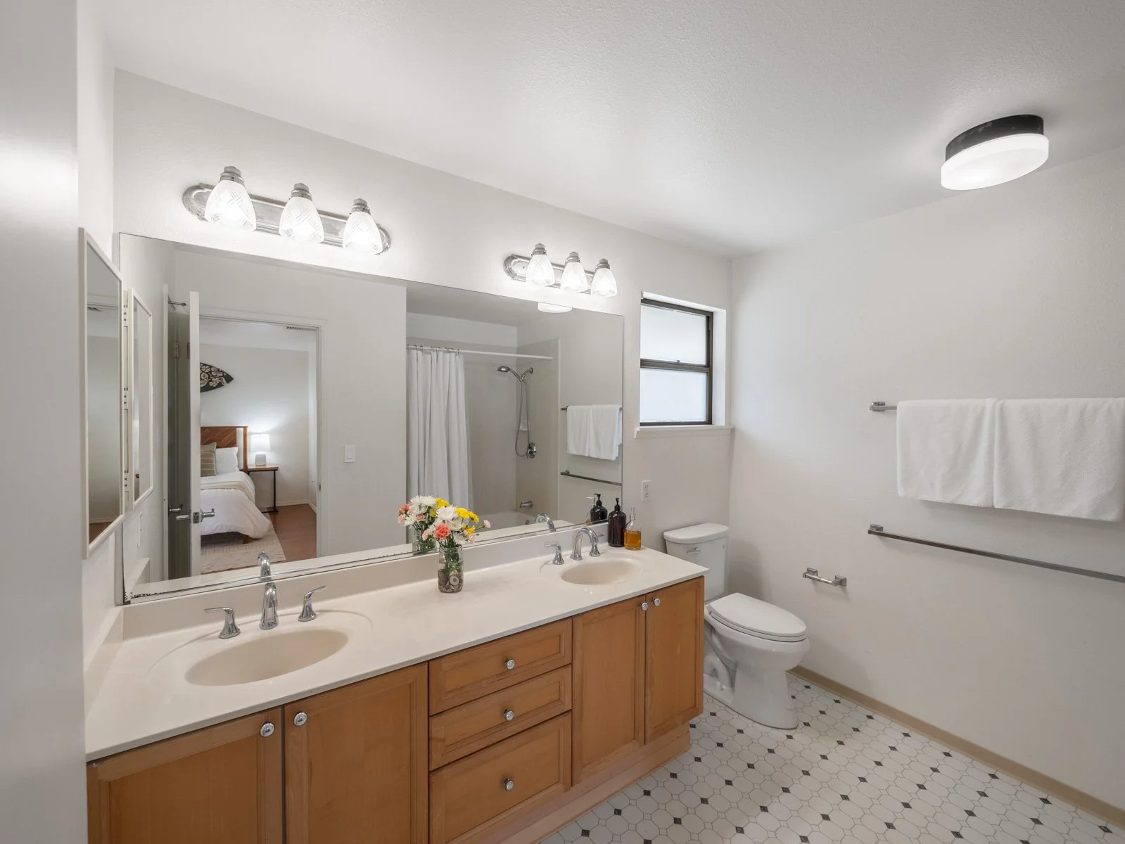 Primary bathroom with double vanity, large mirror and tile floor
