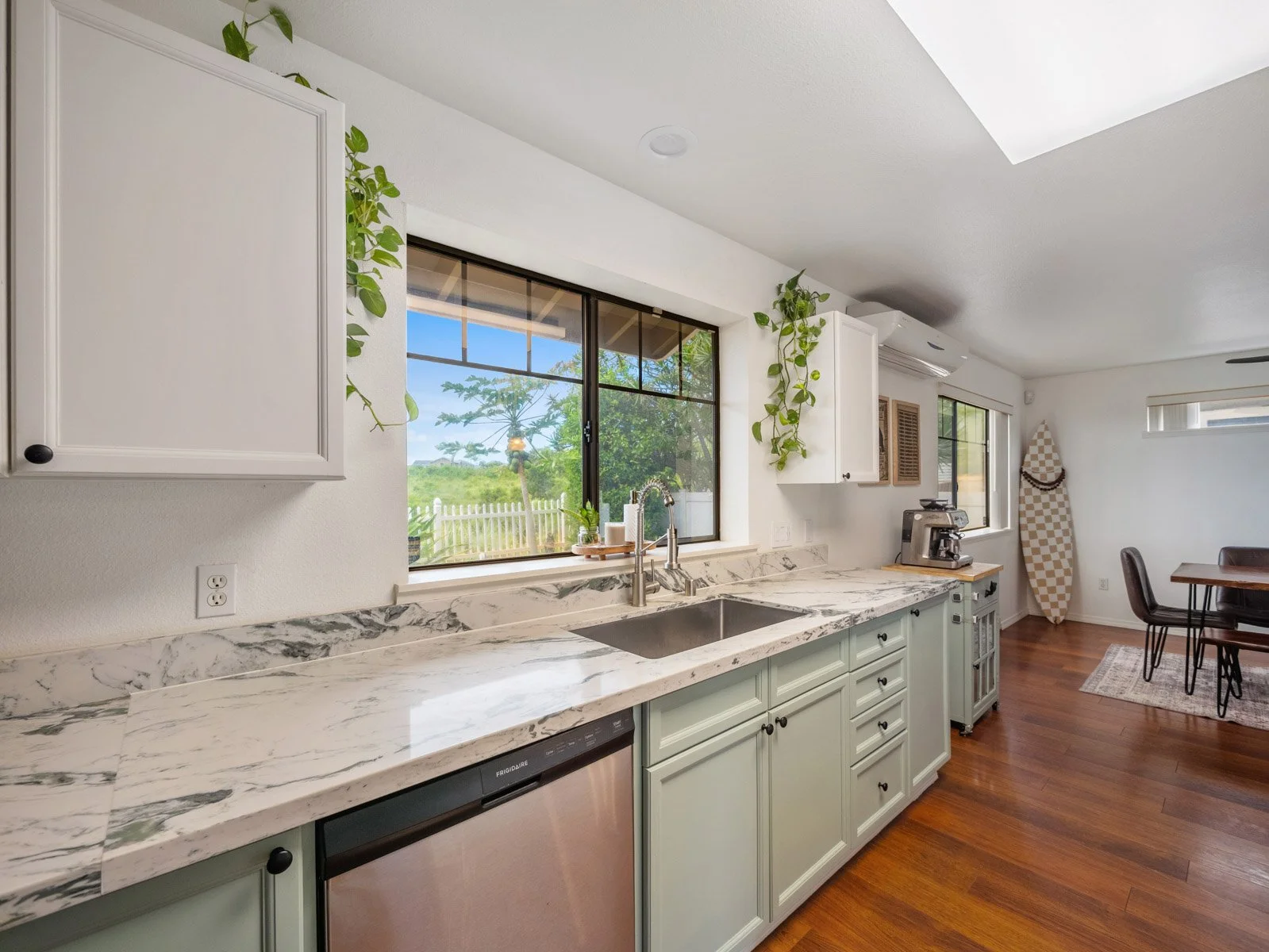 Kitchen counter run with stone surface, dishwasher and window above the sink