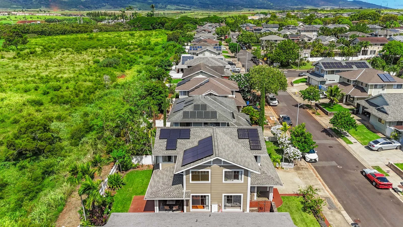 Aerial over the street showing rooftop solar panels across the neighborhood