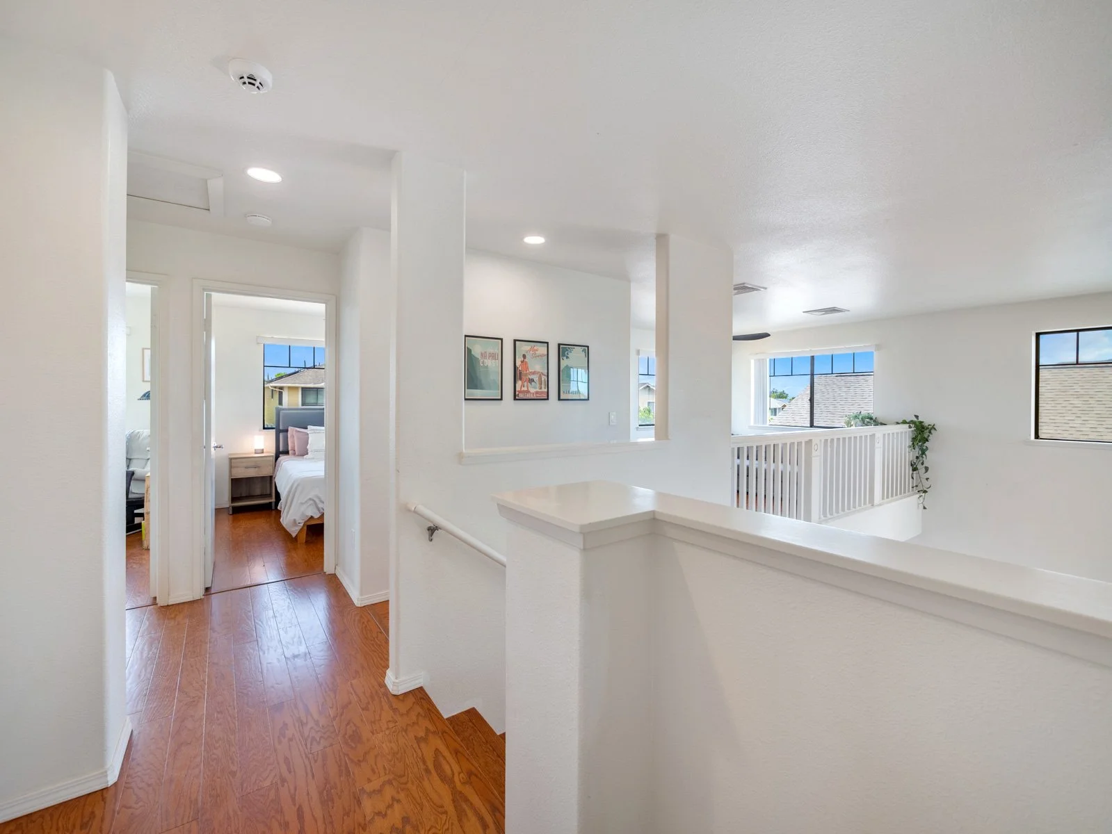 Upstairs landing with open railing, hallway and bedroom doorway