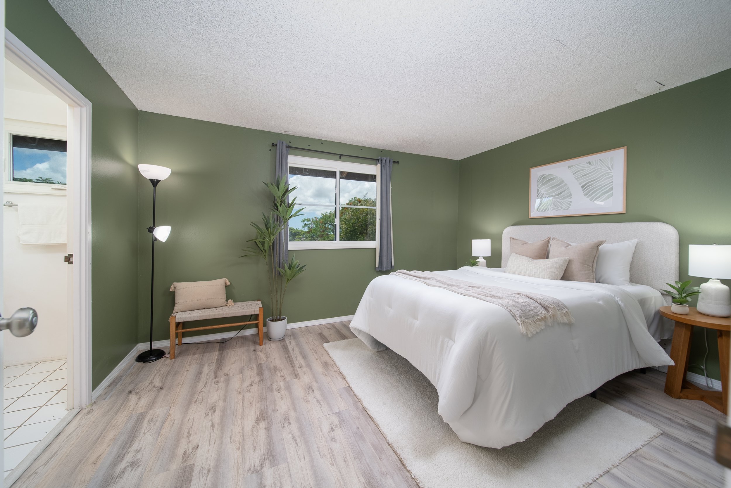 Primary bedroom with green walls, window and seating corner