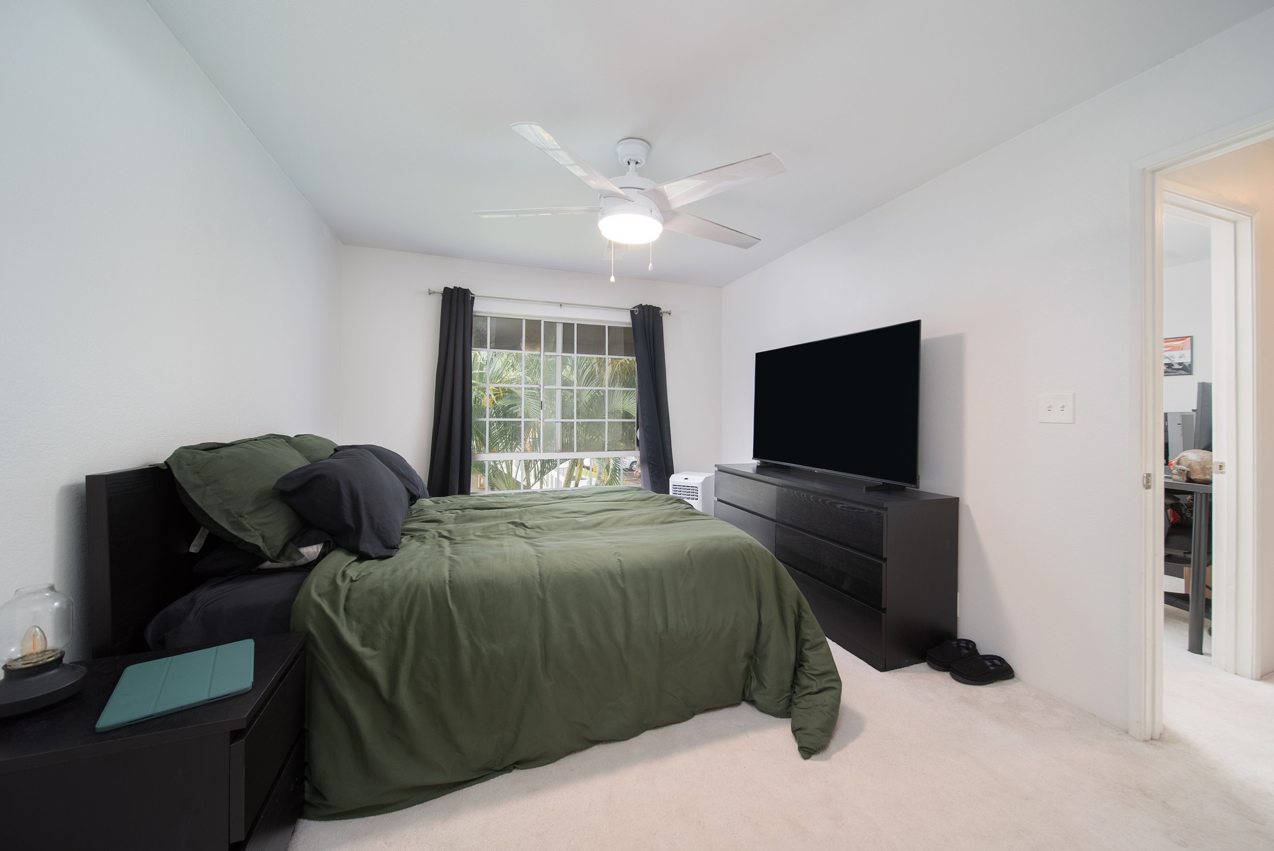 Bedroom with ceiling fan, TV and window overlooking greenery
