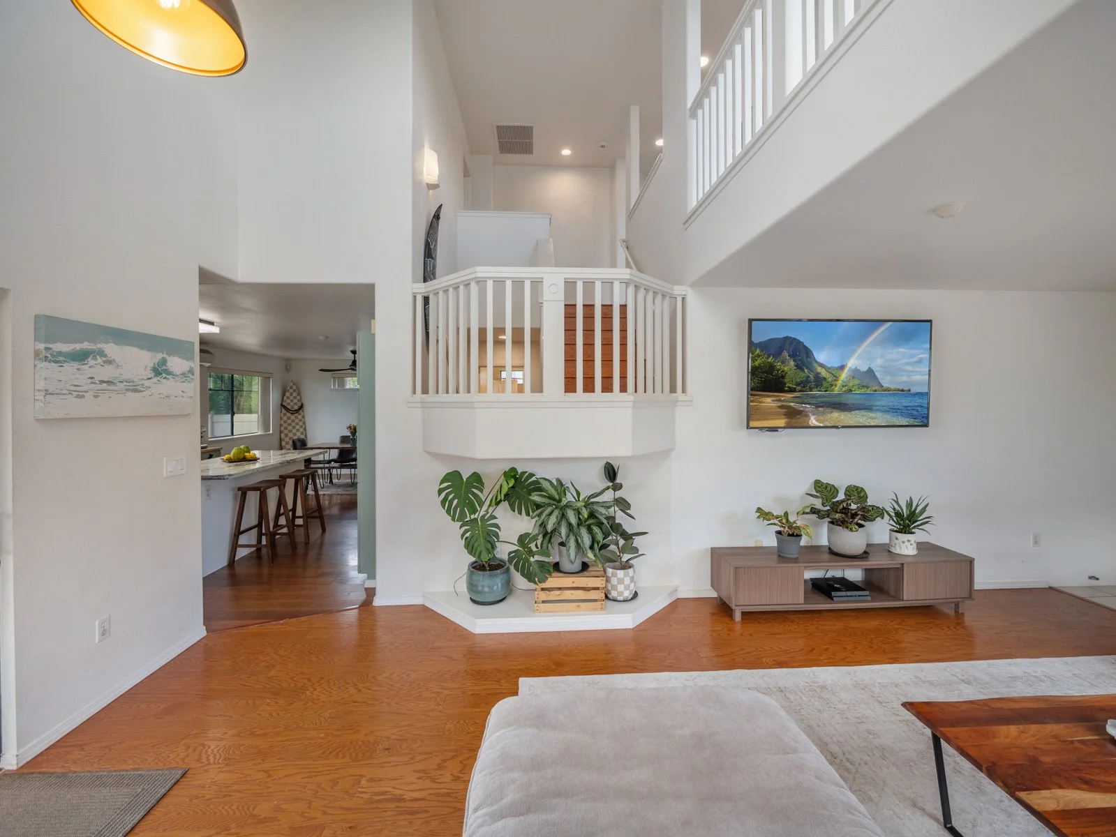 Living room and entry with loft railing above and hardwood floors
