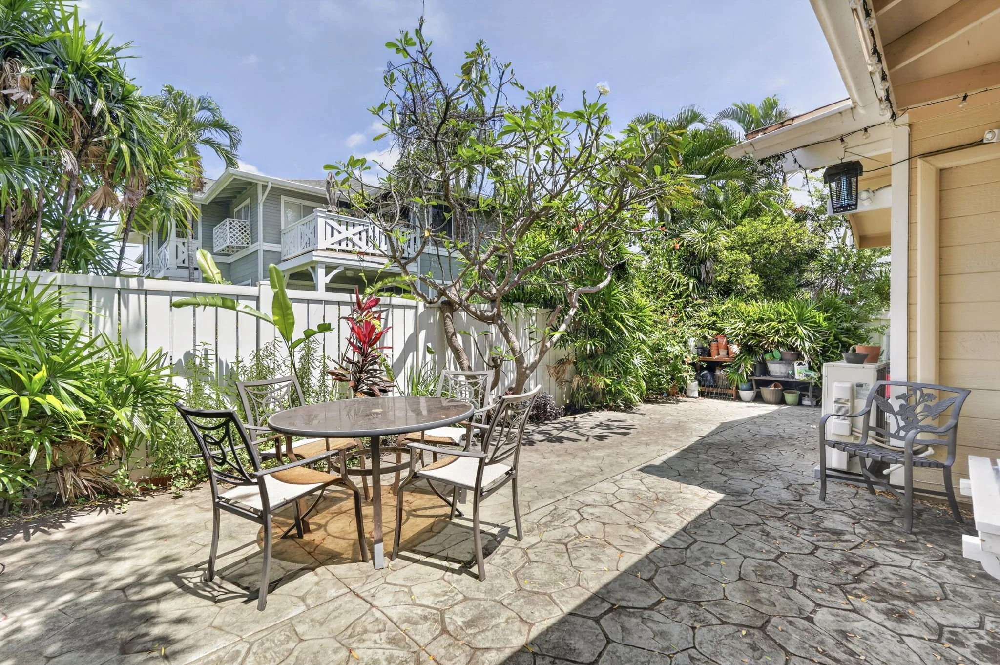 Backyard patio with stone paving, dining set and tropical planting