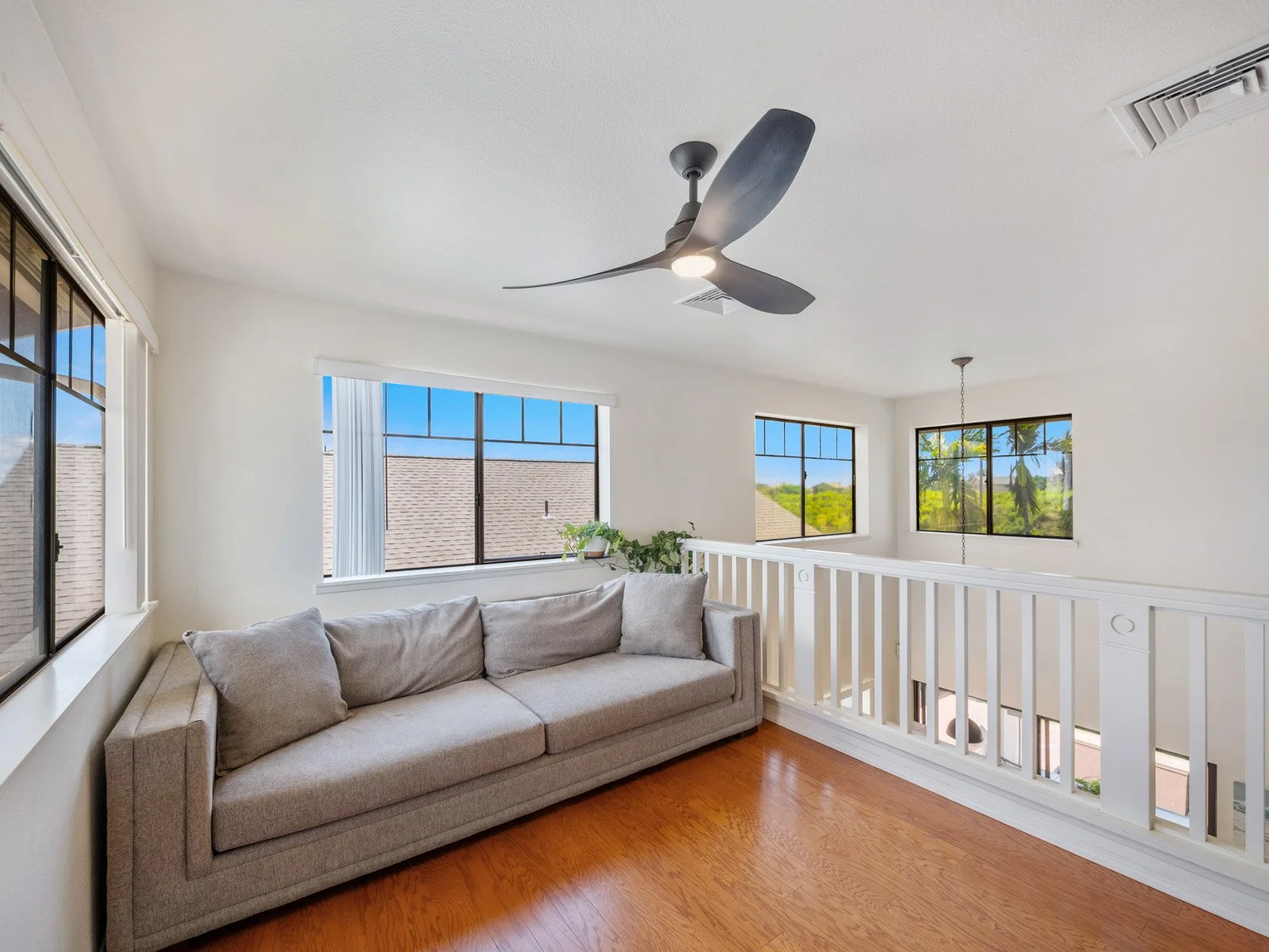 Upstairs loft with sofa, hardwood floors and open railing to below