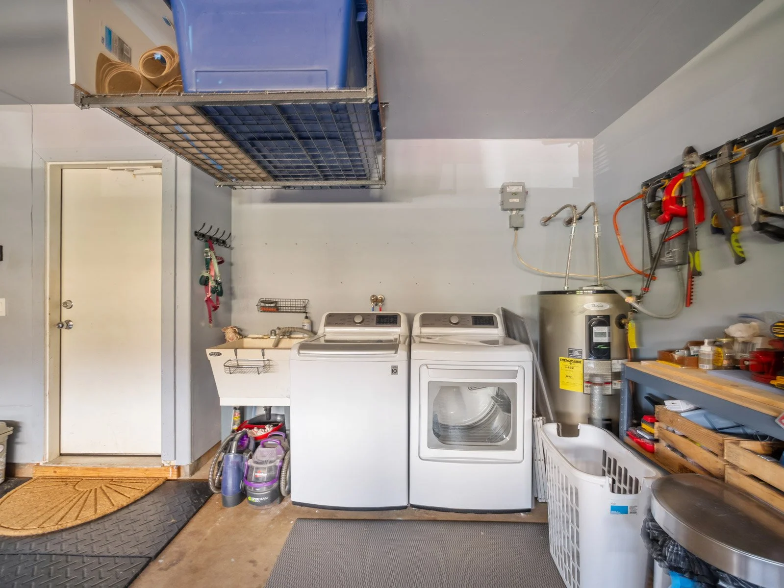 Garage utility area with washer, dryer, water heater and storage shelving