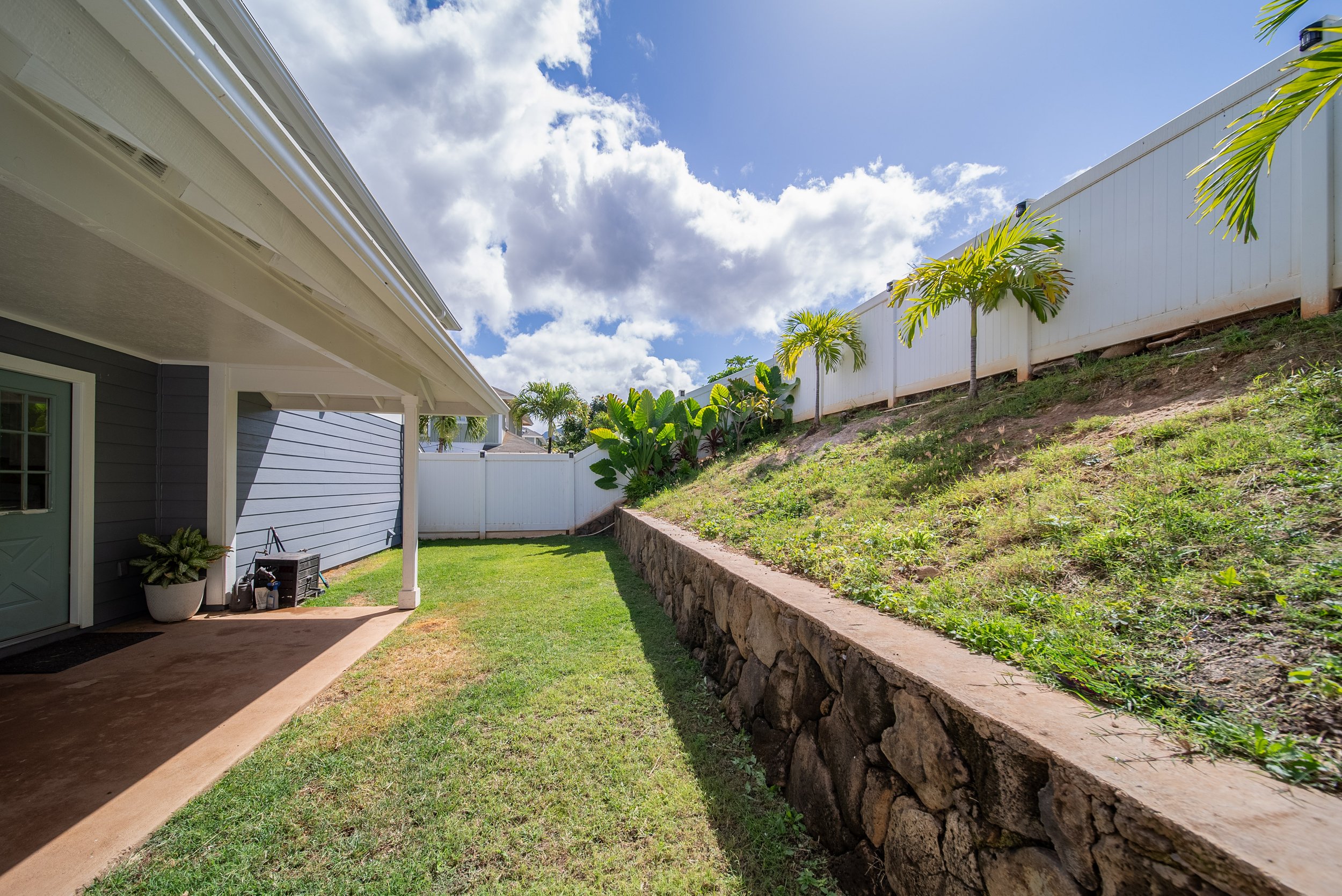 Side yard with covered walkway, lawn and rock retaining wall, Maili Sea Palekai