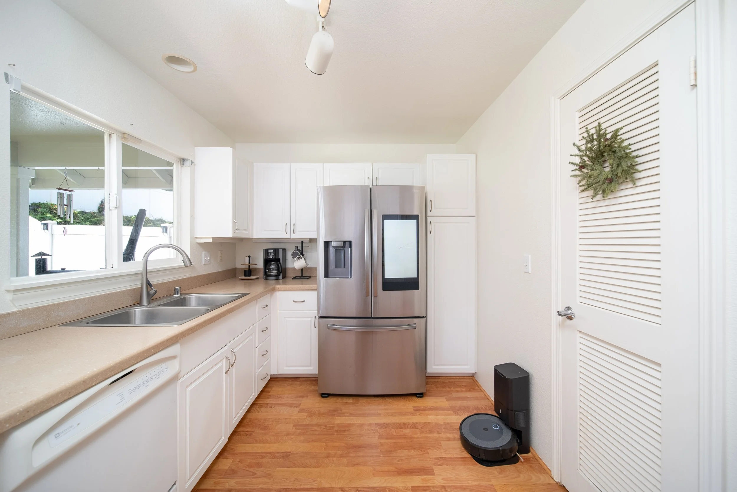 Galley kitchen with stainless refrigerator, double sink and louvered pantry door