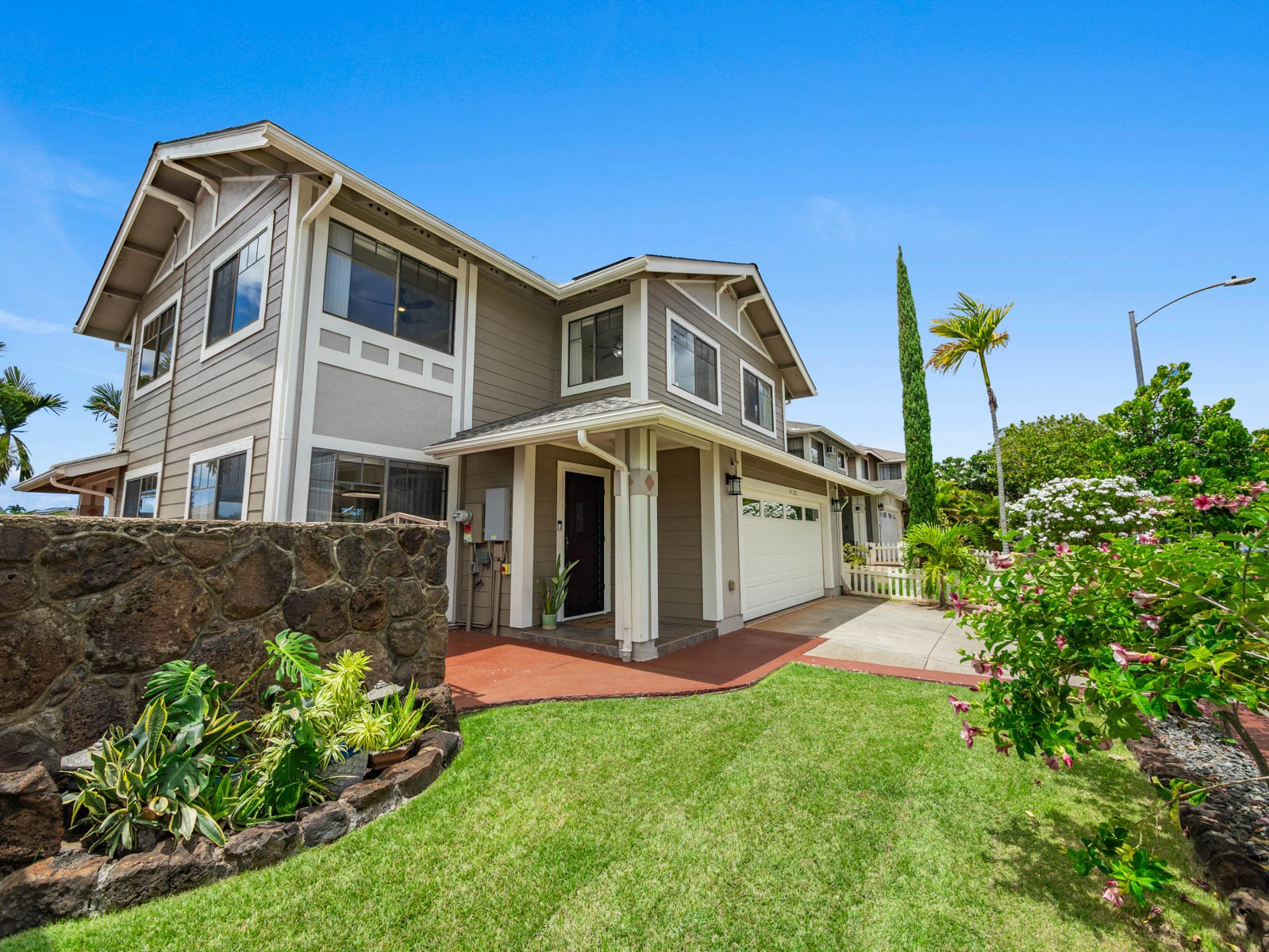 Daytime exterior with front lawn, rock retaining wall and landscaping