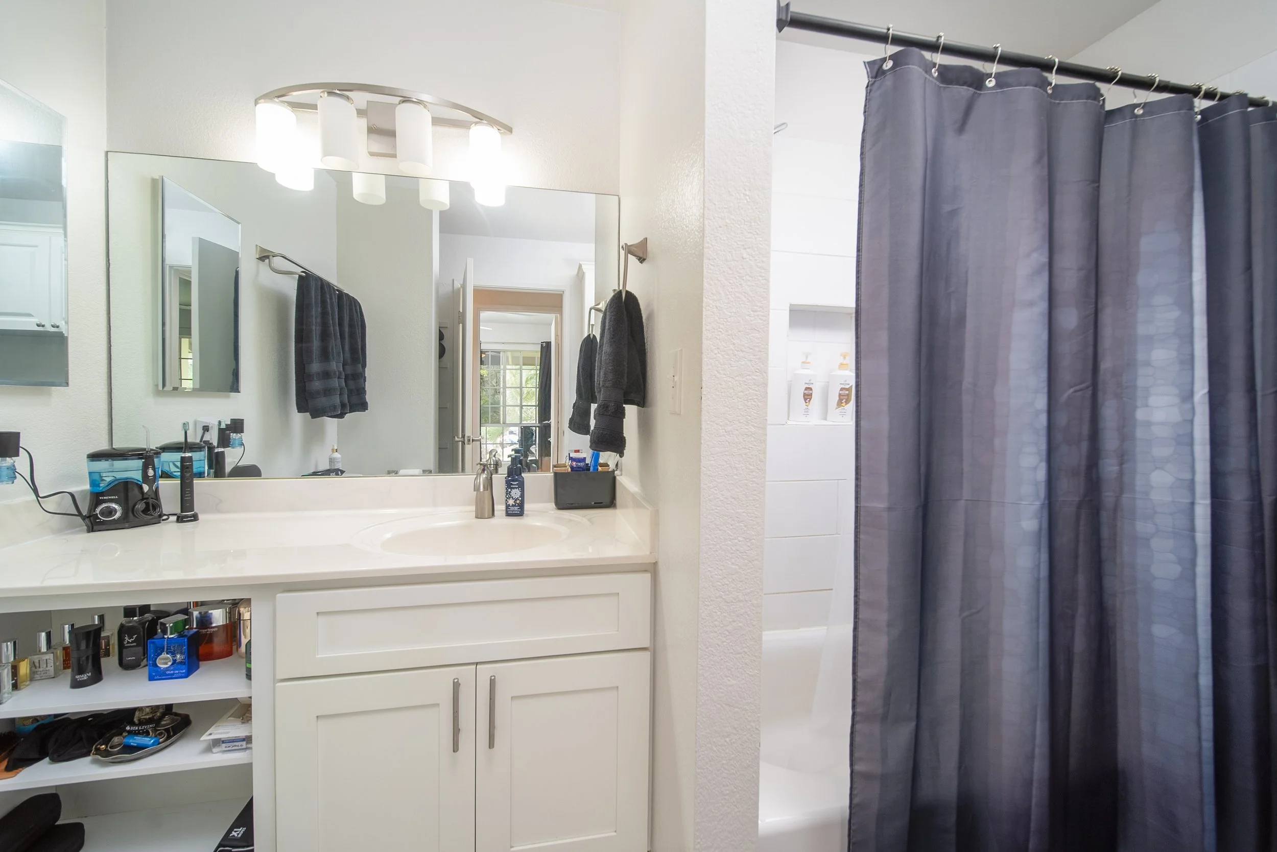 Bathroom vanity with large mirror, shower and tub behind the curtain