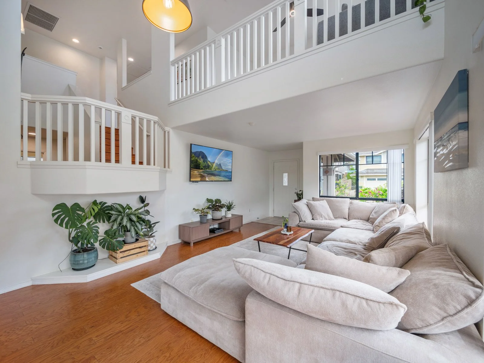 Living room open two stories with sectional, loft railing and hardwood floors