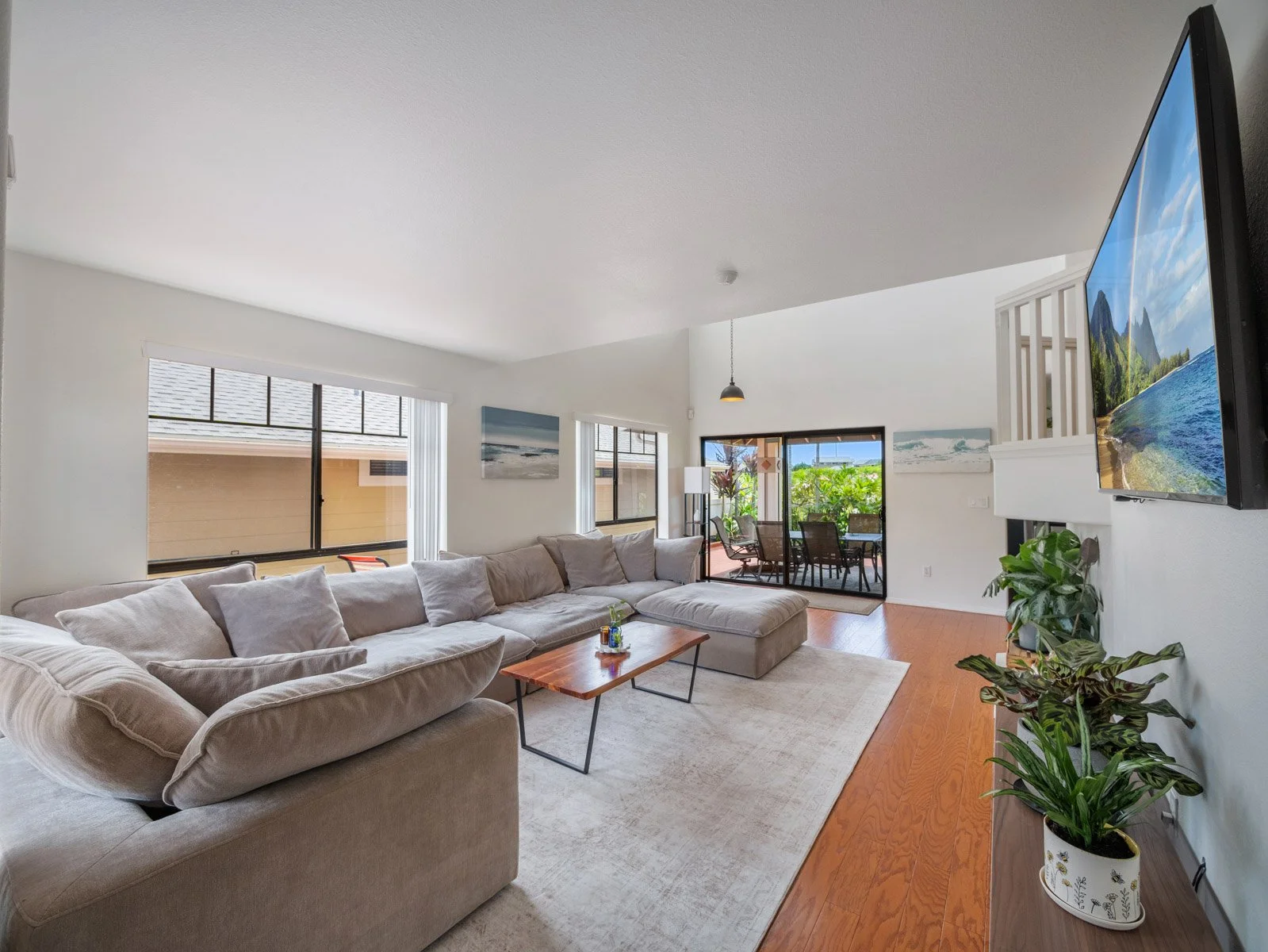 Living room with sectional, wall mounted television and hardwood floors