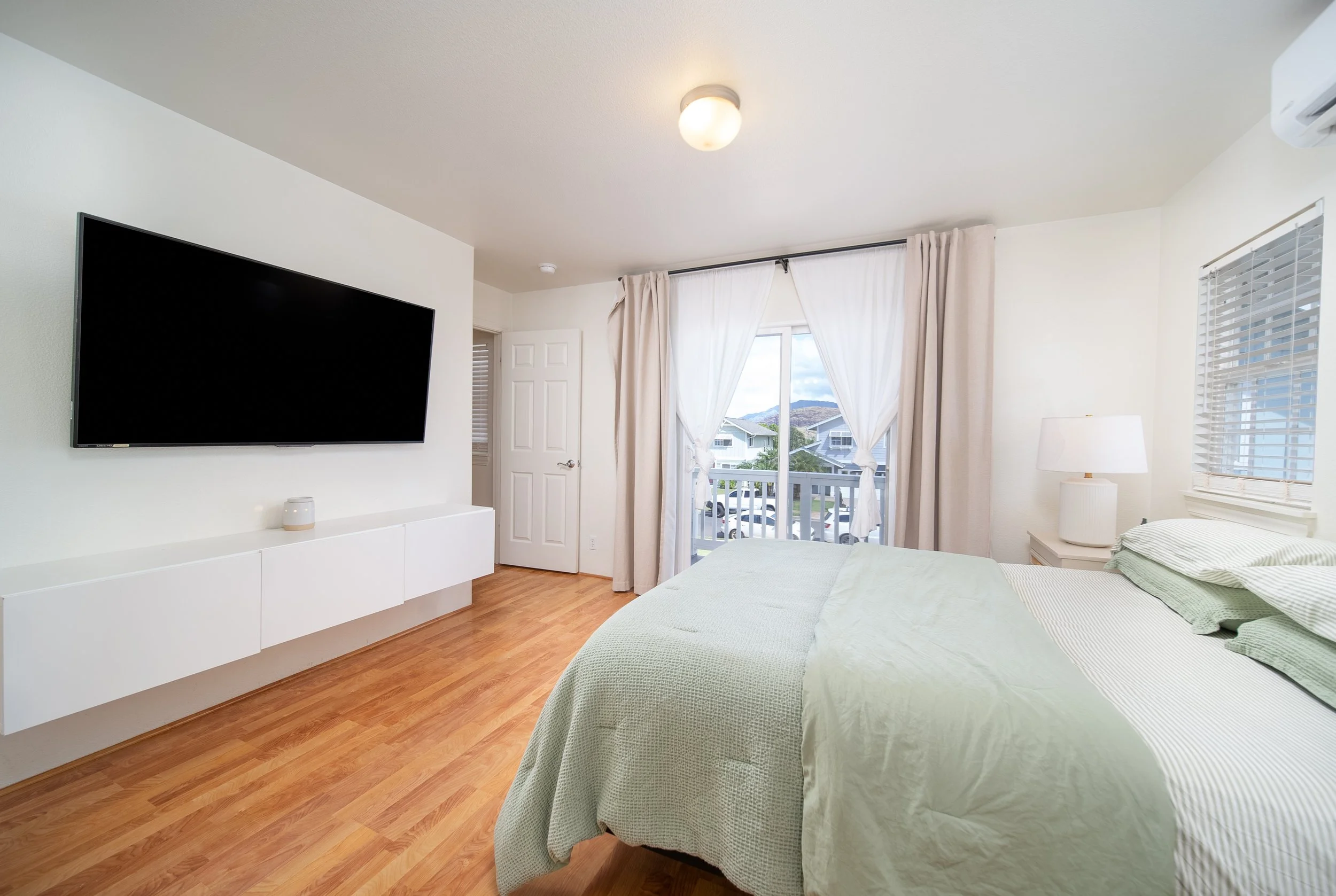 Primary bedroom with wall mounted TV and doors to the private balcony