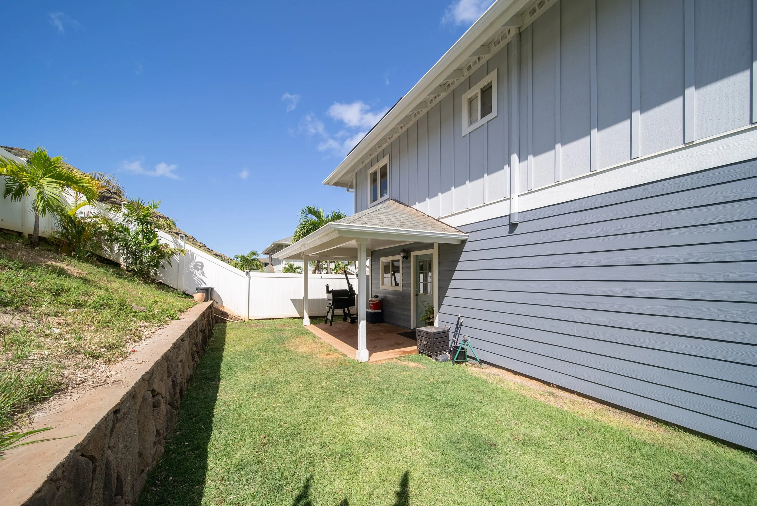 Side of the Home with covered patio, lawn and sloped landscaping