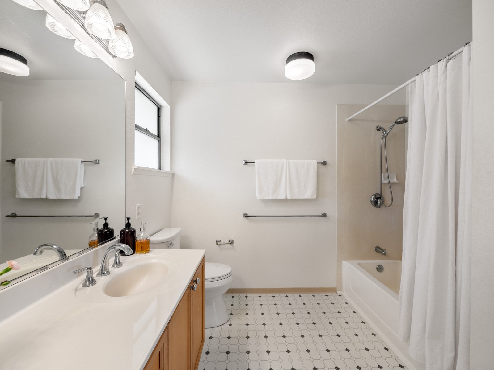 Bathroom with vanity, mirror, tub and shower with tile flooring
