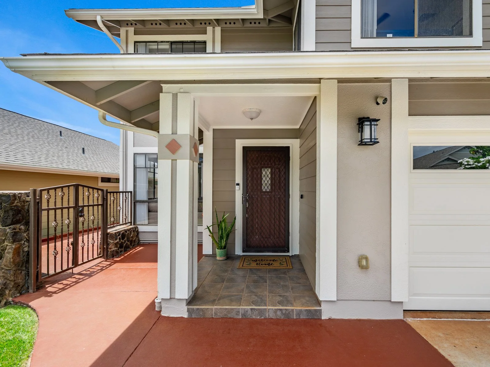 Covered front entry with wood door, tile landing and gated side path