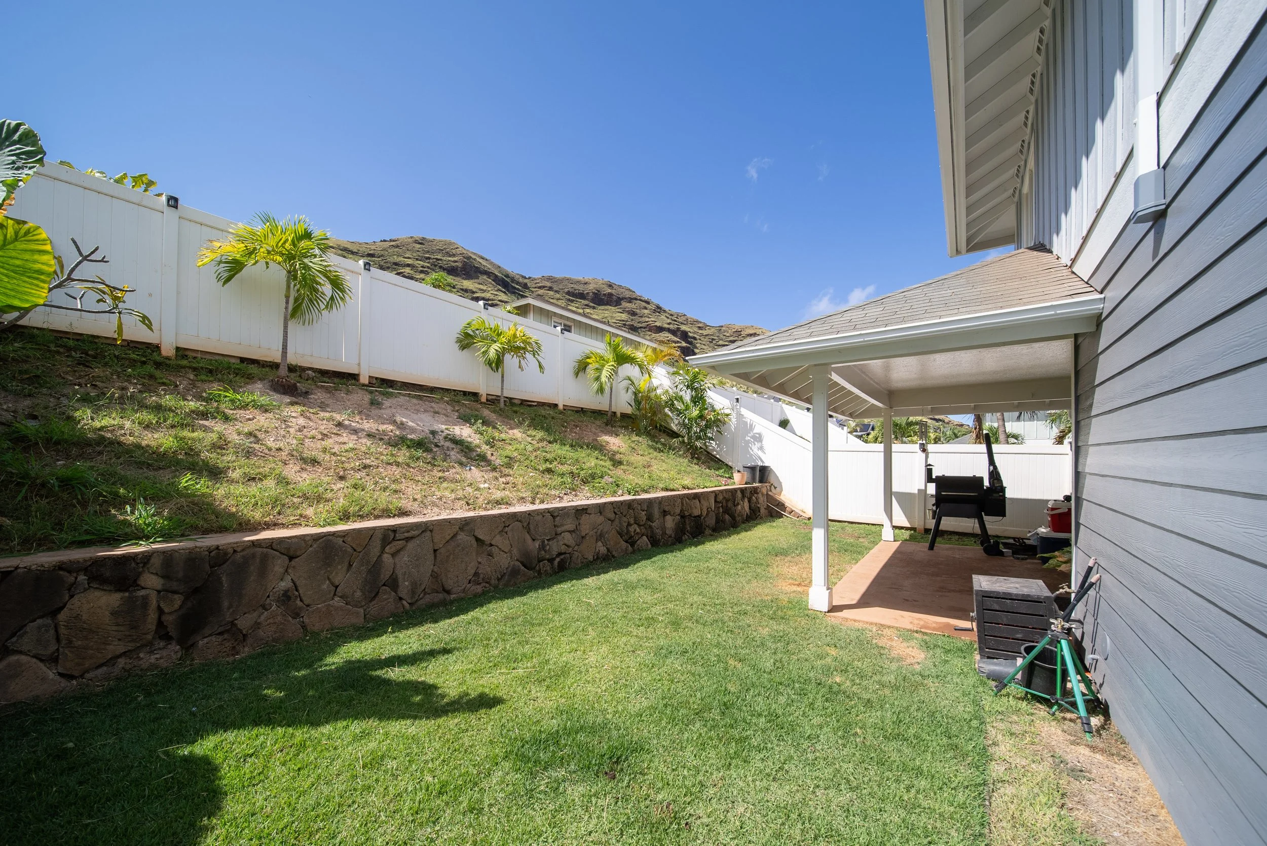 Backyard lawn with covered patio and rock retaining wall, Waianae