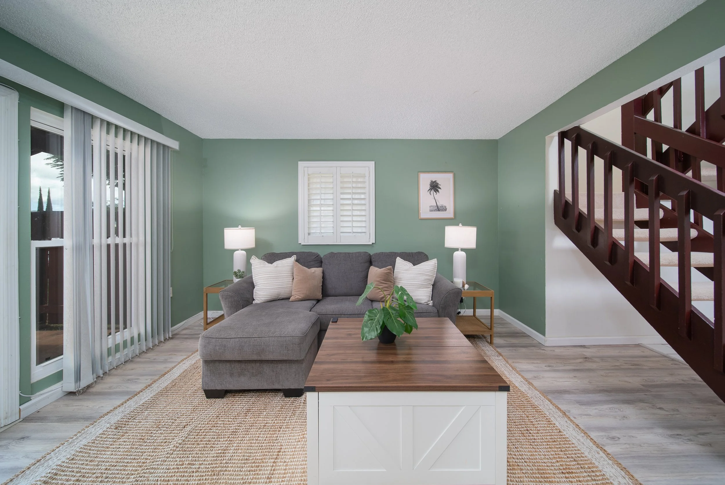 Living room with sectional and staircase, sliding doors to the lanai