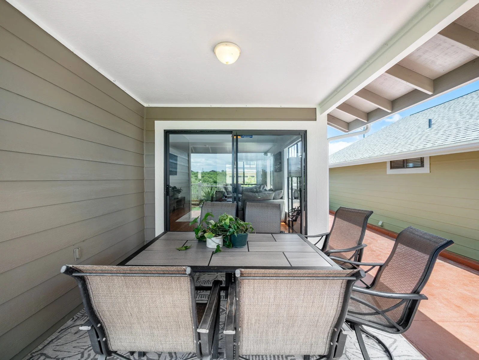 Covered lanai with dining table and slider into the living room