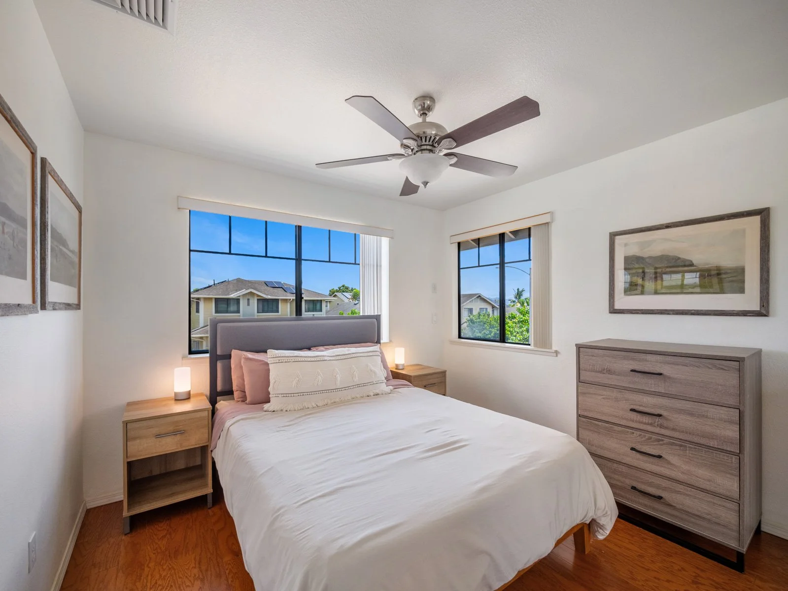 Bedroom with ceiling fan, windows, bed and wood dresser