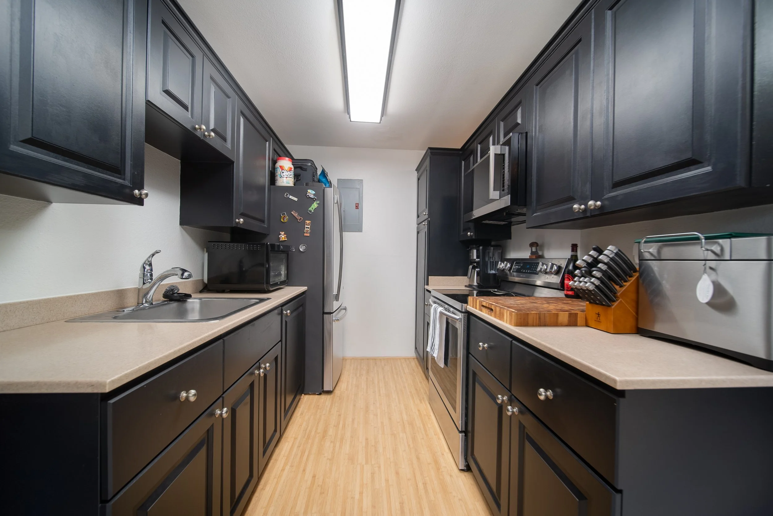 Remodeled galley kitchen with dark cabinetry and stainless steel appliances