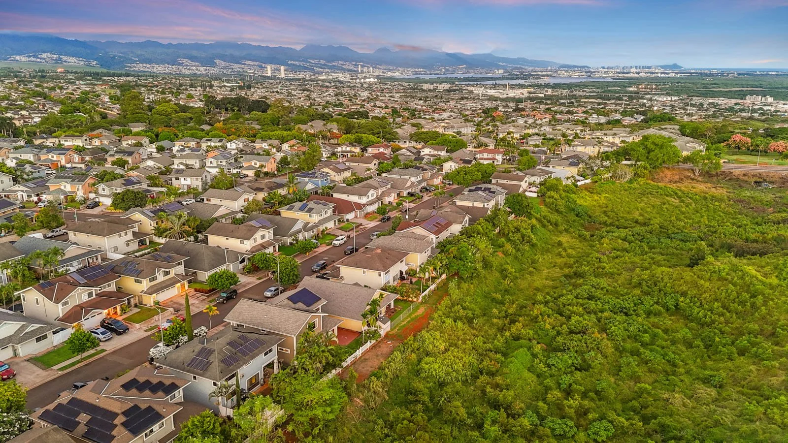 Aerial over Royal Kunia rooftops with open green space and city beyond