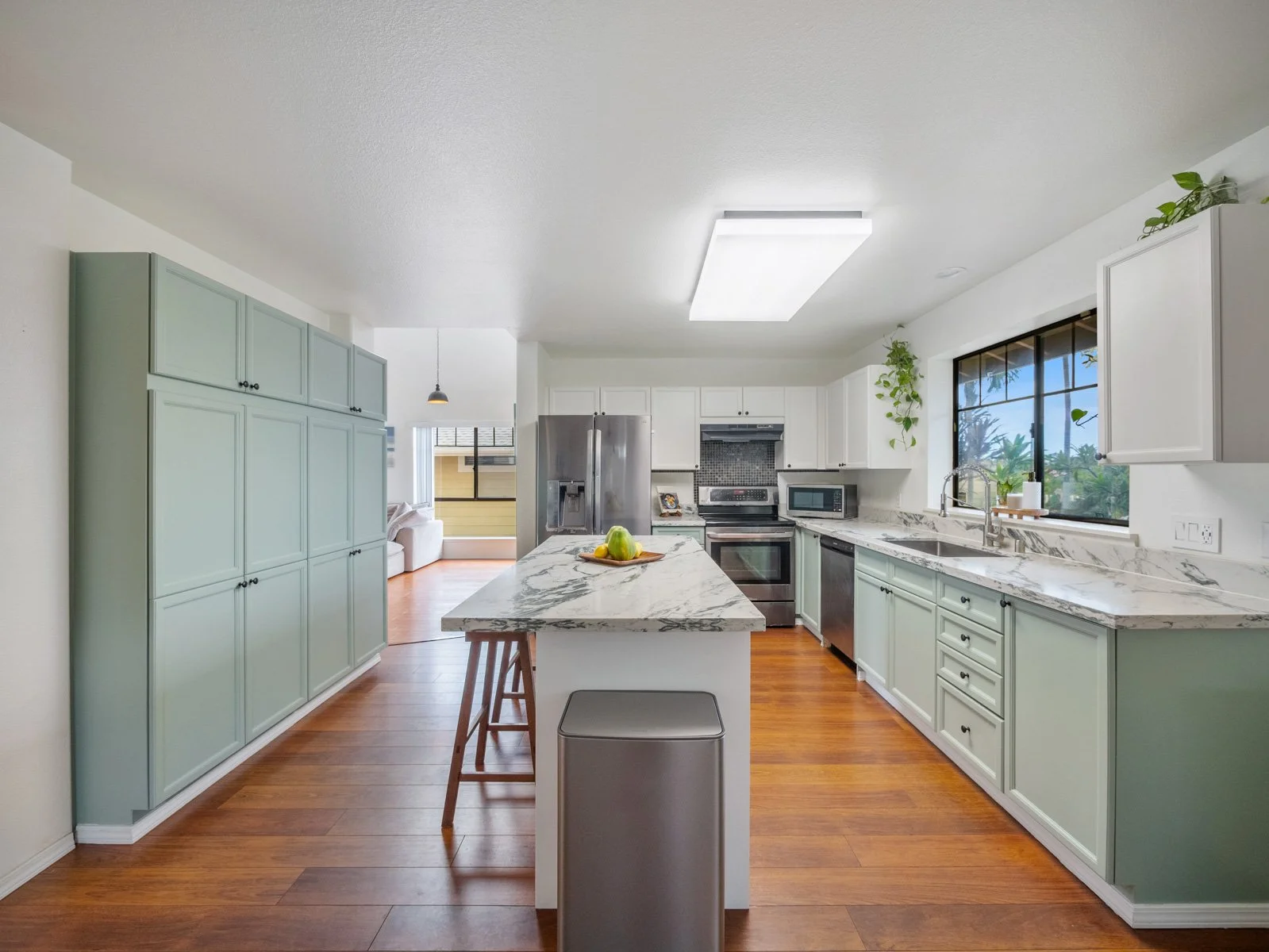 Kitchen with island, stone counters and floor to ceiling sage cabinetry