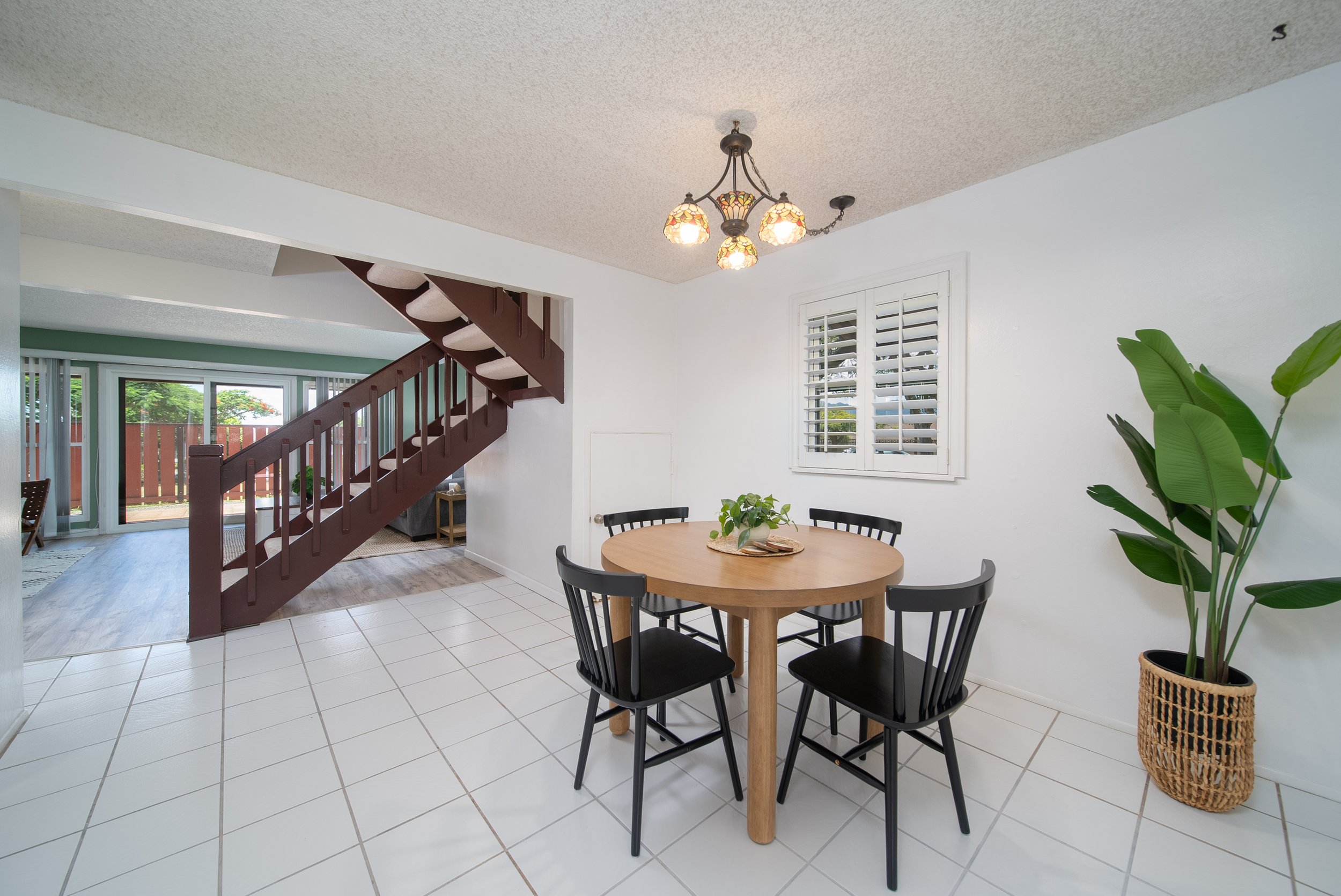 Dining area with round table and tile floor, looking through to the living room and staircase