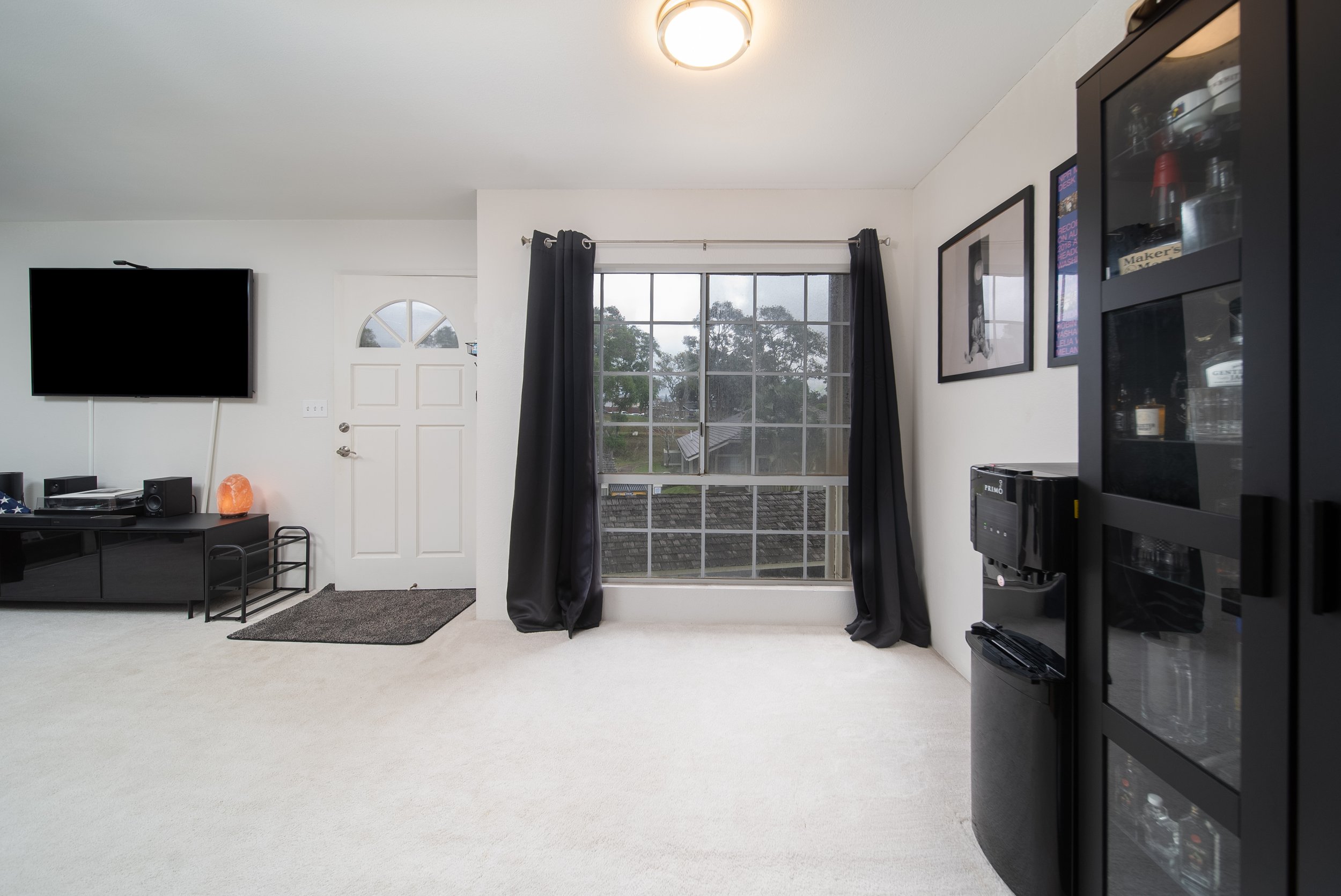 Living area with entry door, window and wall mounted TV