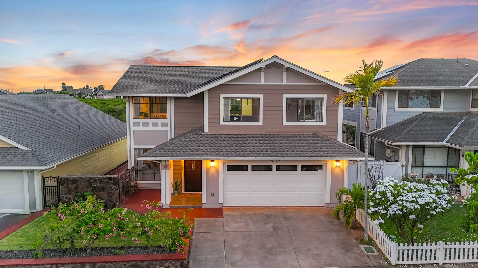 Twilight front elevation with garage, driveway and white picket fencing