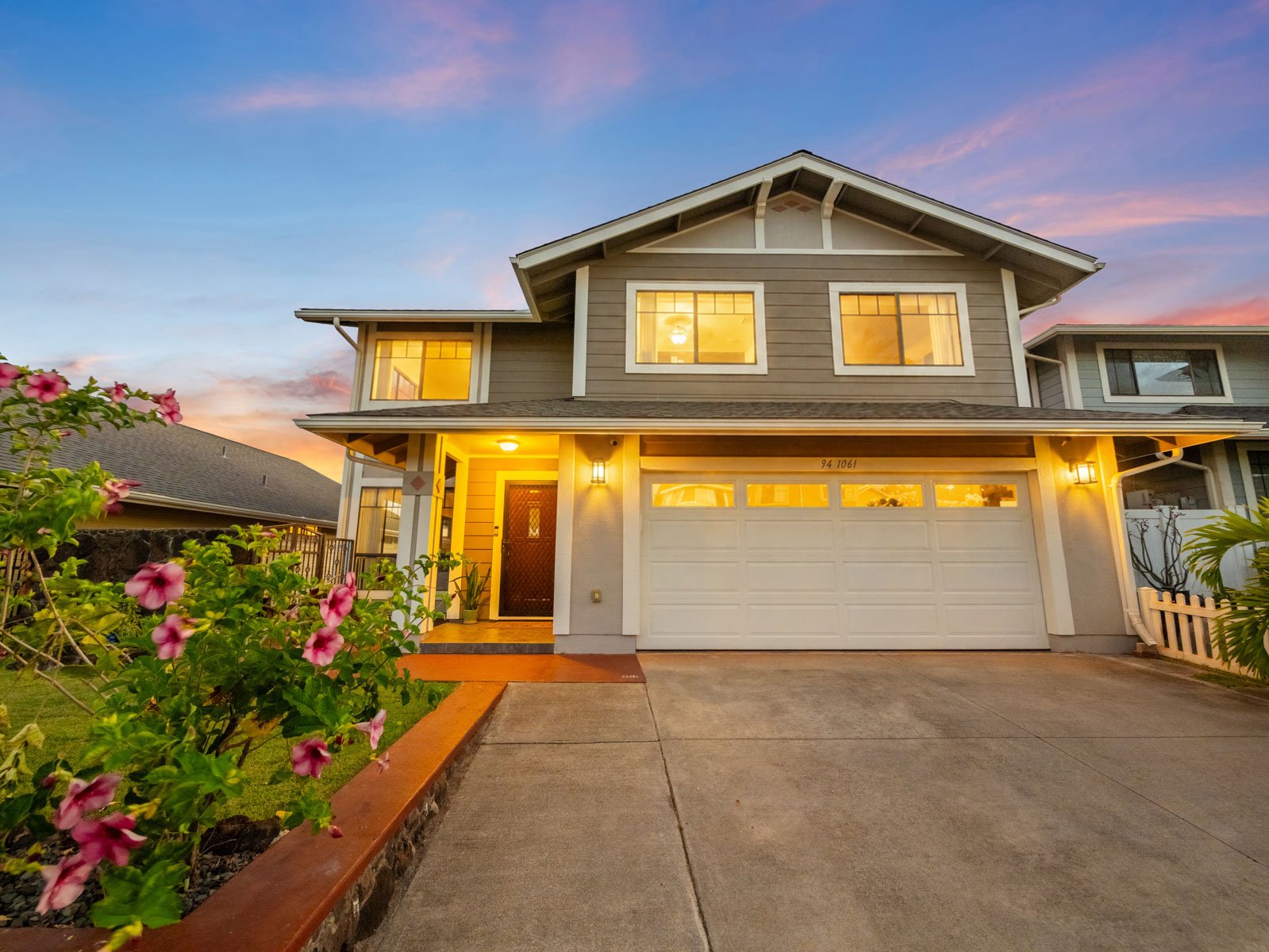 Twilight front elevation with flowering plants along the walkway