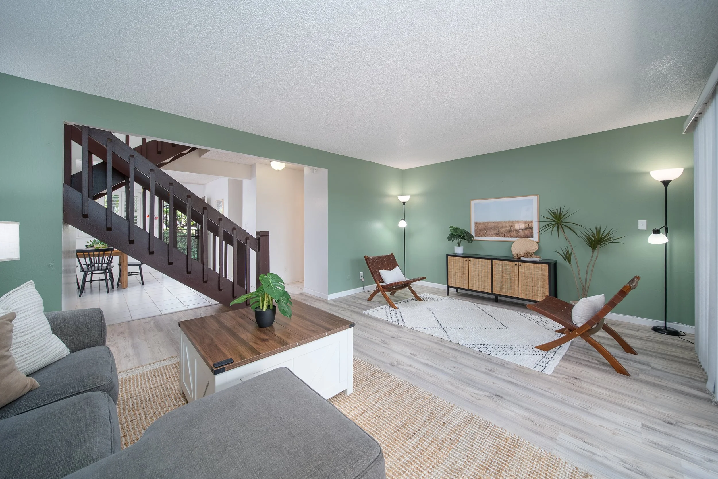 Living room with staircase, console table and seating, wood look flooring