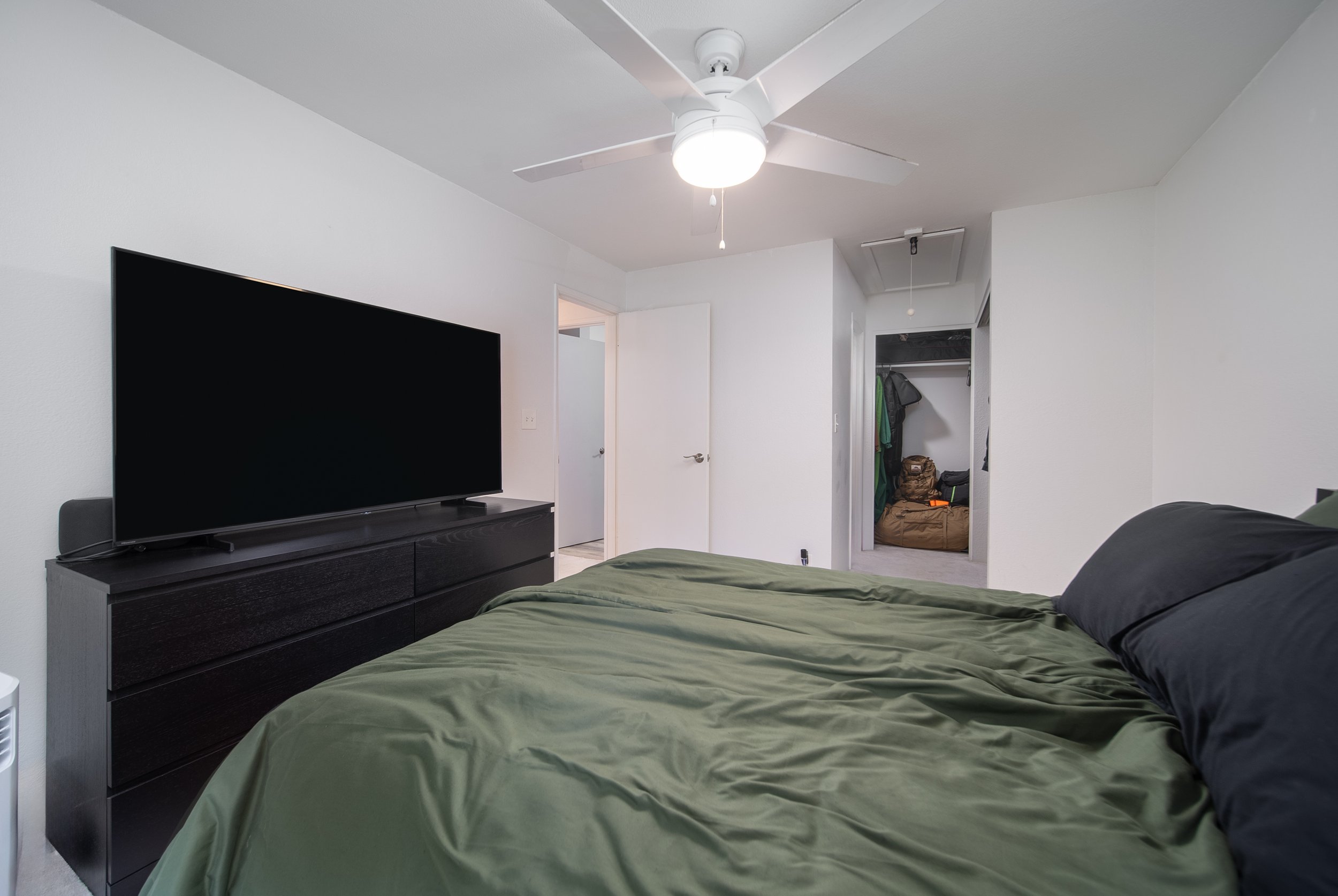 Bedroom with dresser, wall mounted TV and doorway to the hall