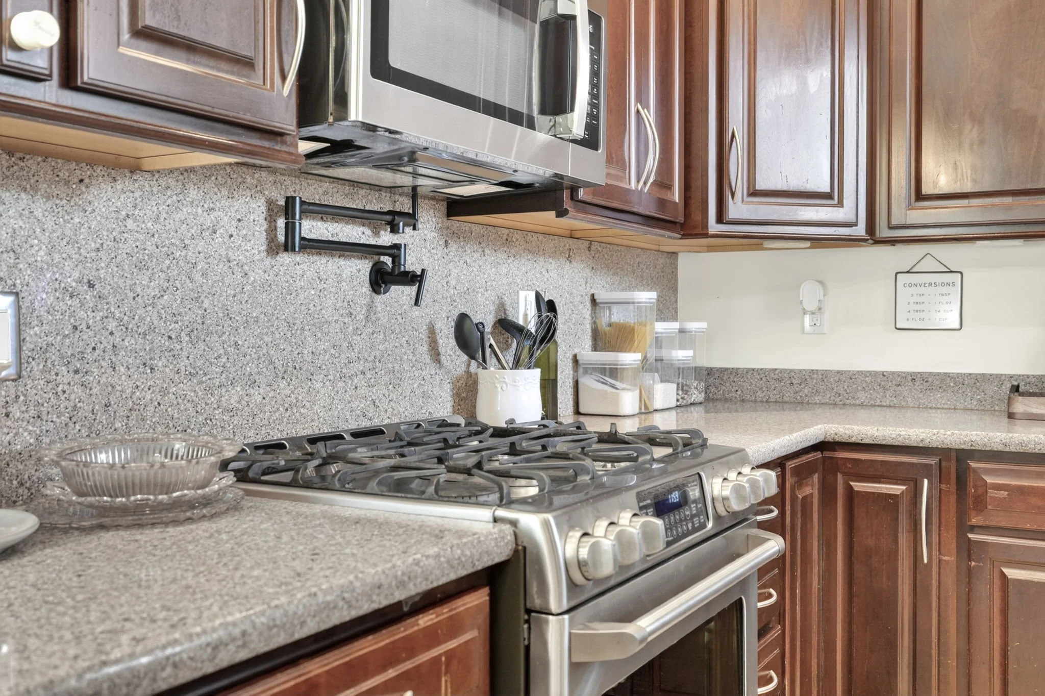 Gas range with pot filler and granite counters in the upgraded kitchen