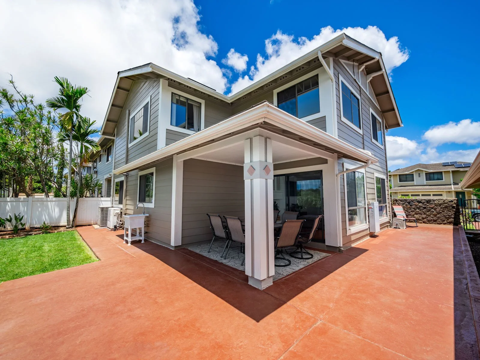 Rear exterior with covered lanai, stamped patio and green lawn