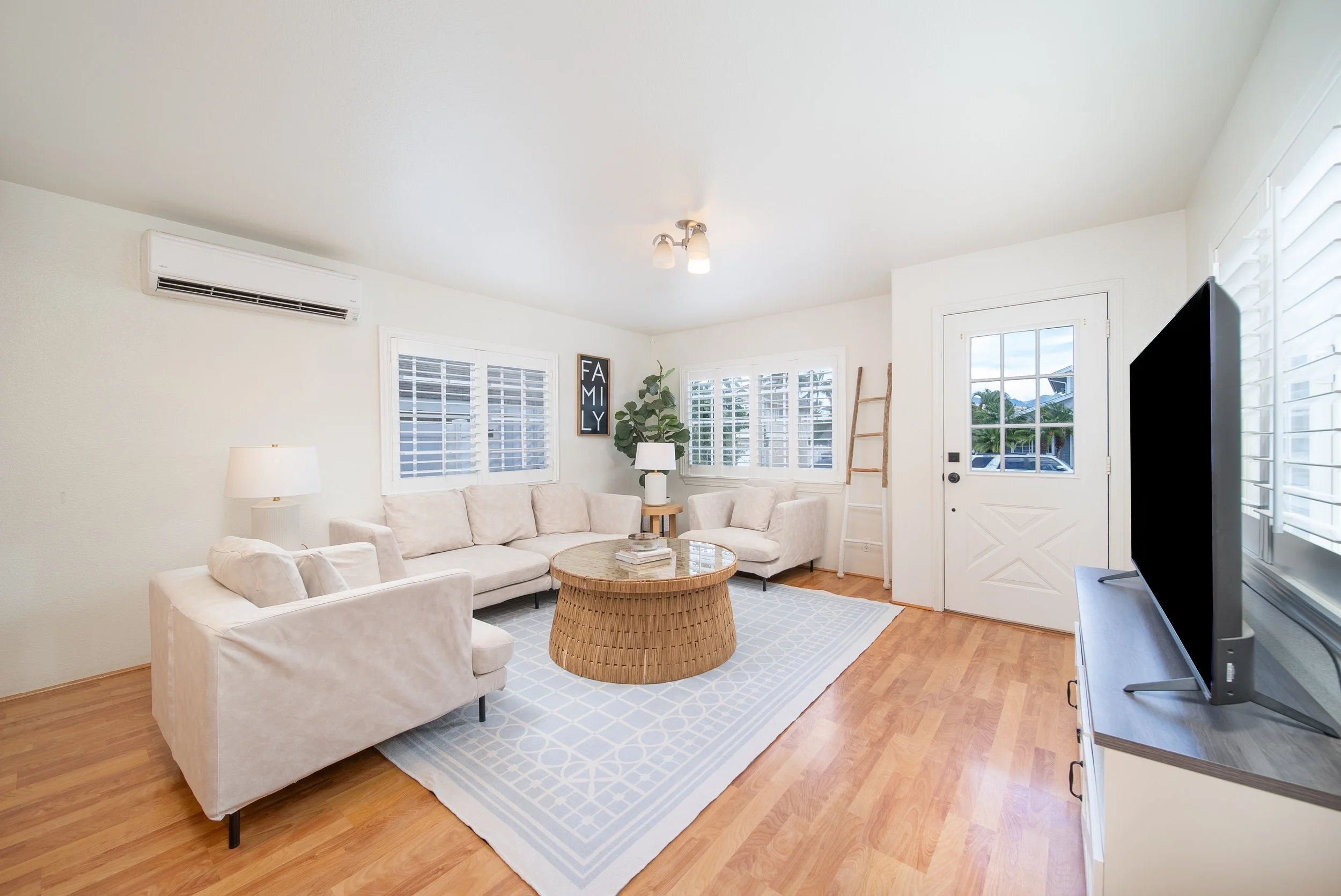Living room with sectional, split AC and front entry with plantation shutters