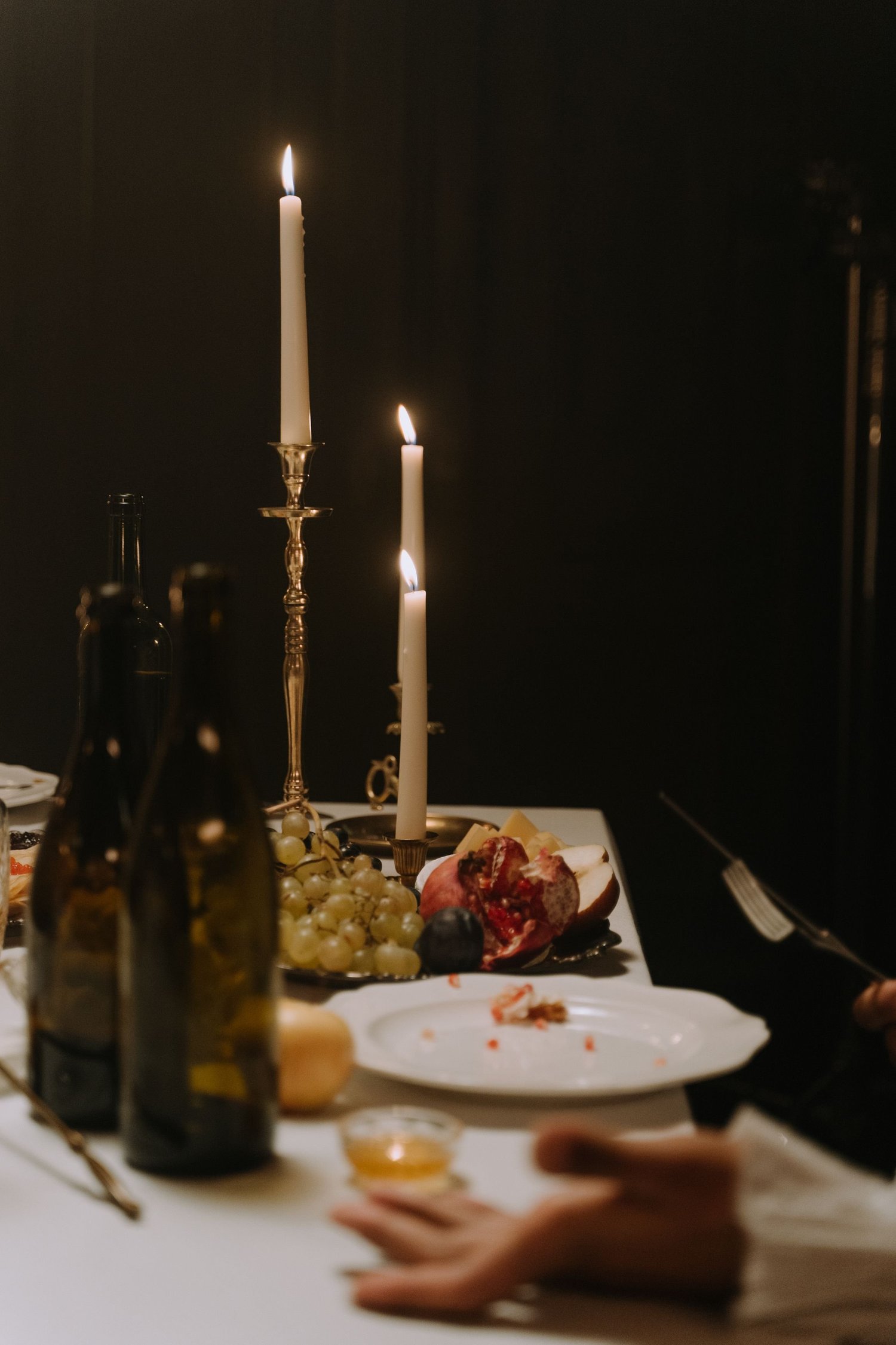 Slender candlelight and fruit at an intimate dinner table