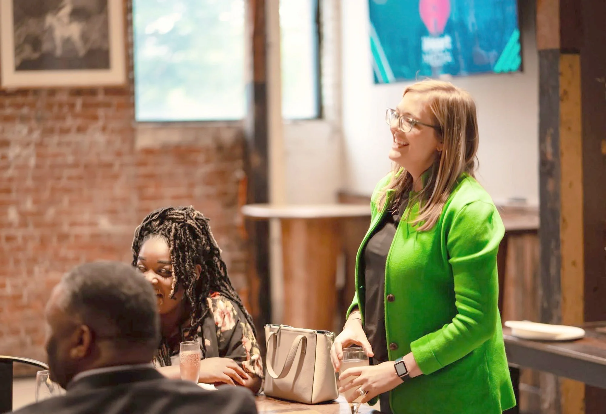 Jessica Whatley laughing with guests around a table at a networking event