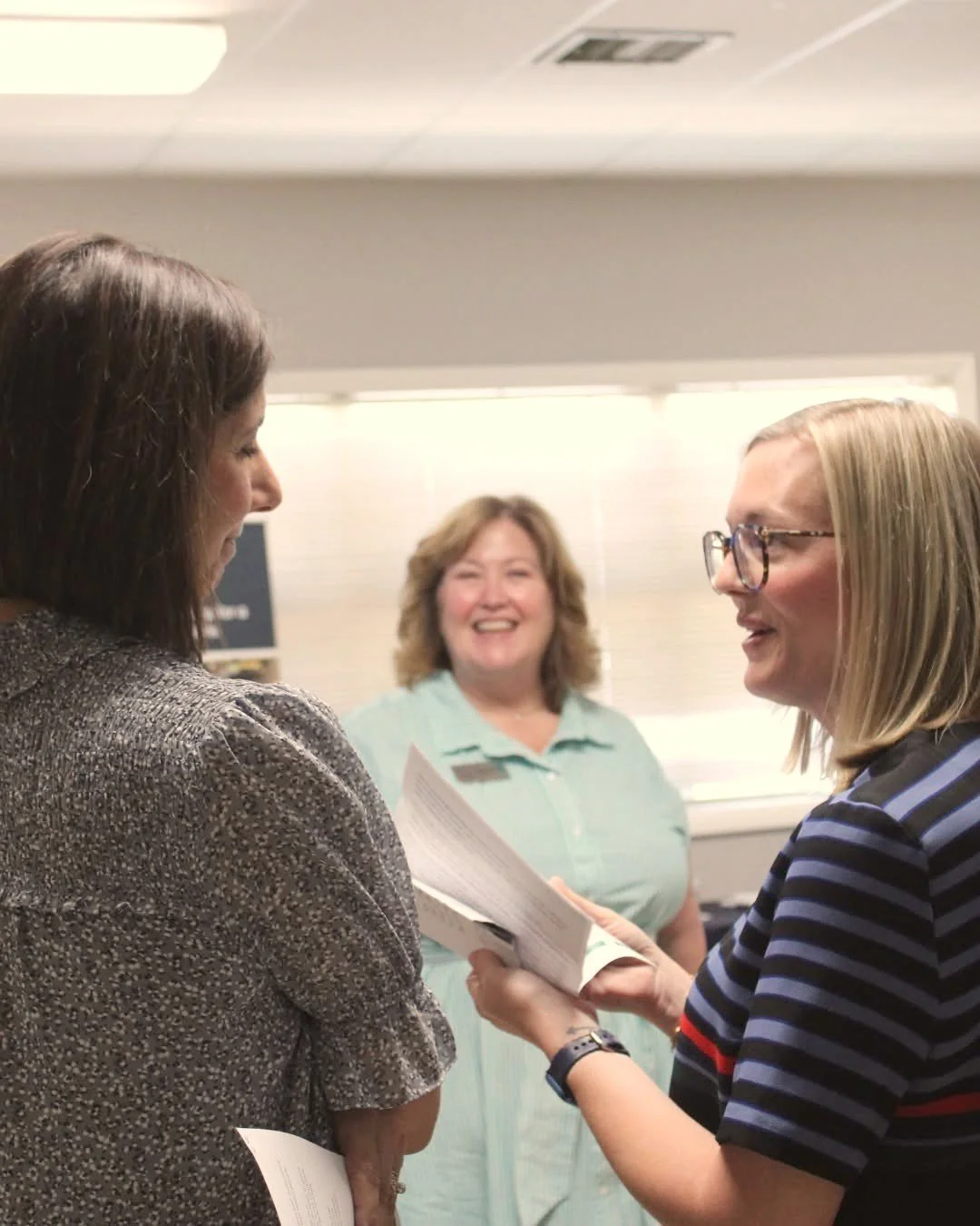 Jessica Whatley talking through notes with two women at a meeting