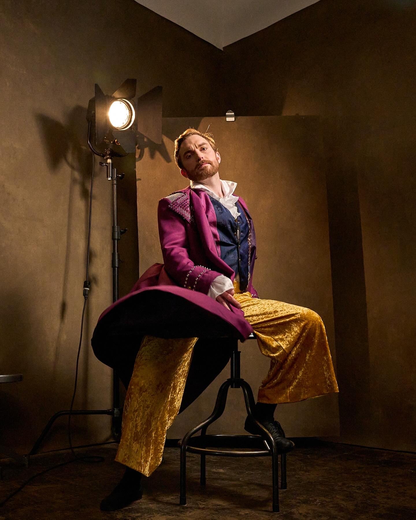 Mark Radcliffe in costume, seated under a studio light