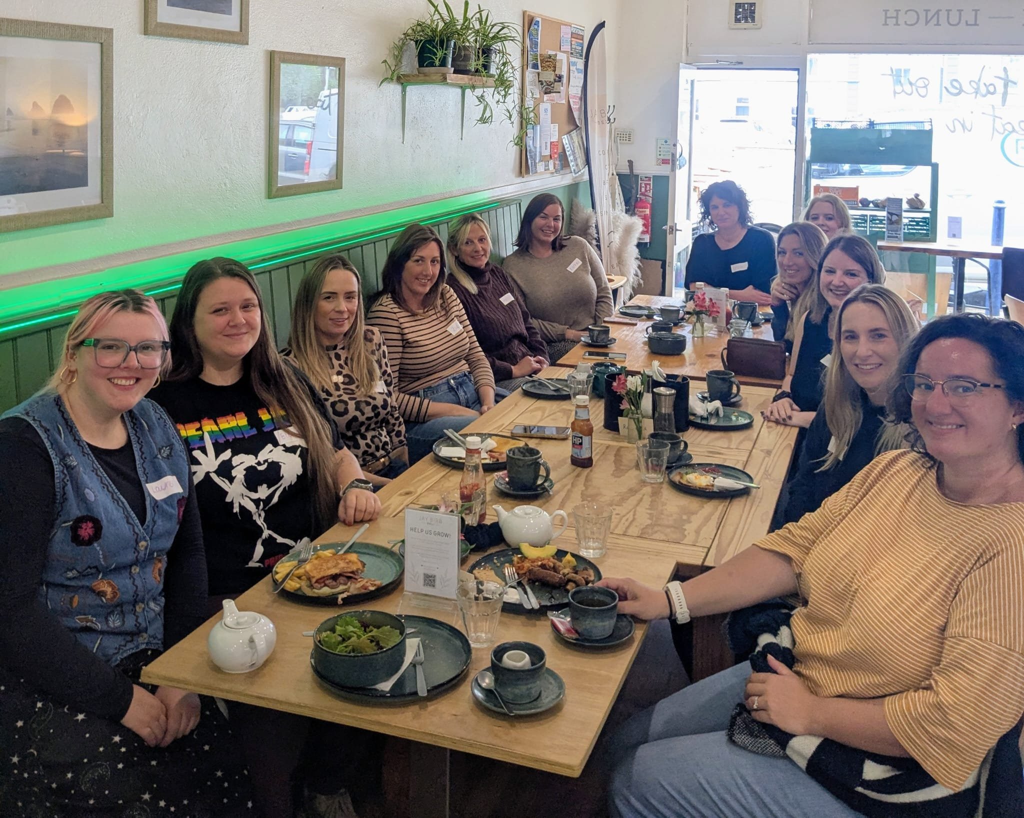 Dreckly Wild Women members at Brunch Club, round a cafe table with coffee and brunch