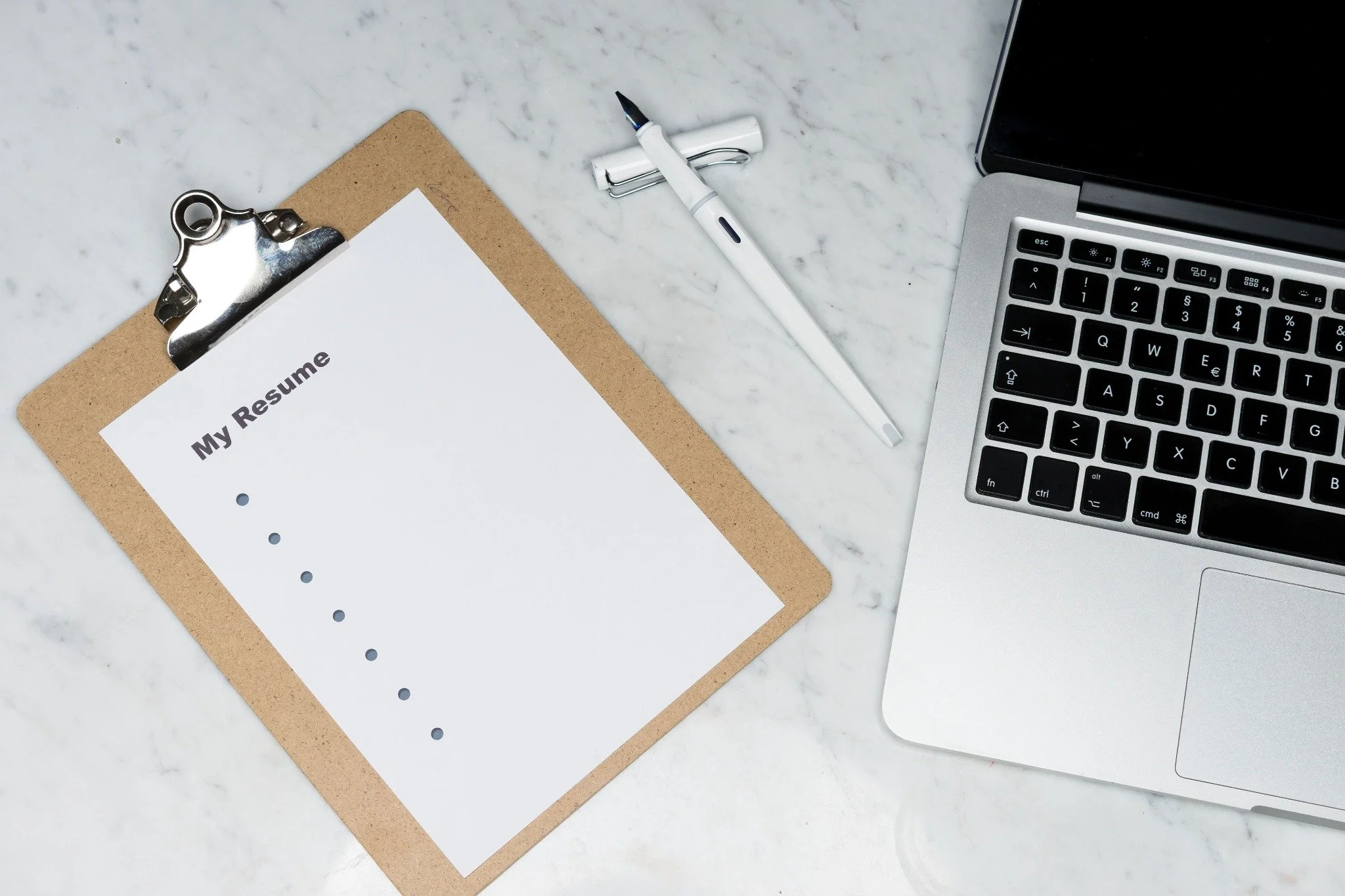 A résumé, pen, and laptop ready for a job application