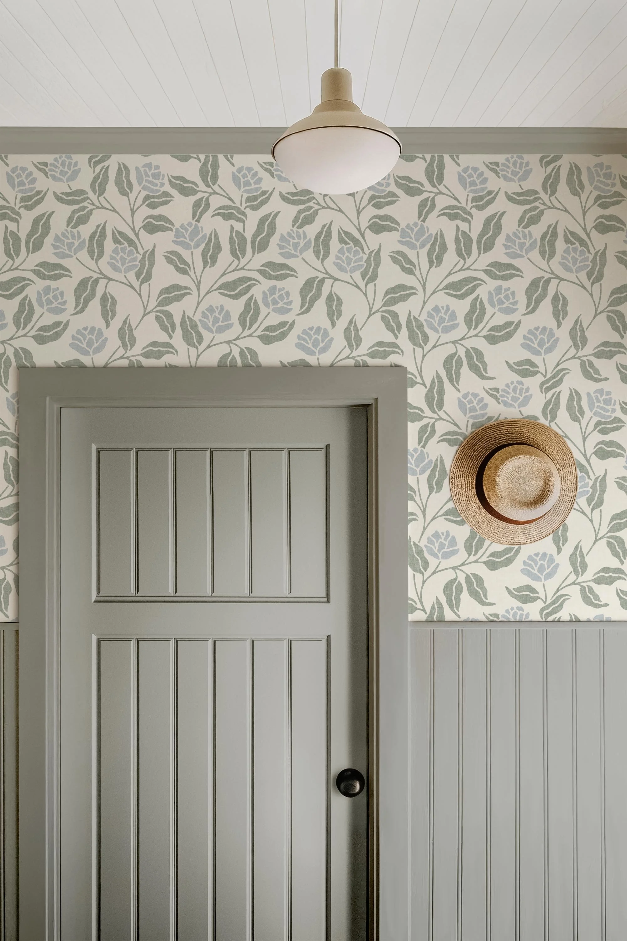 Sage green and soft blue botanical wallpaper for an English country entryway, paired with grey beadboard panelling and a painted wood door.