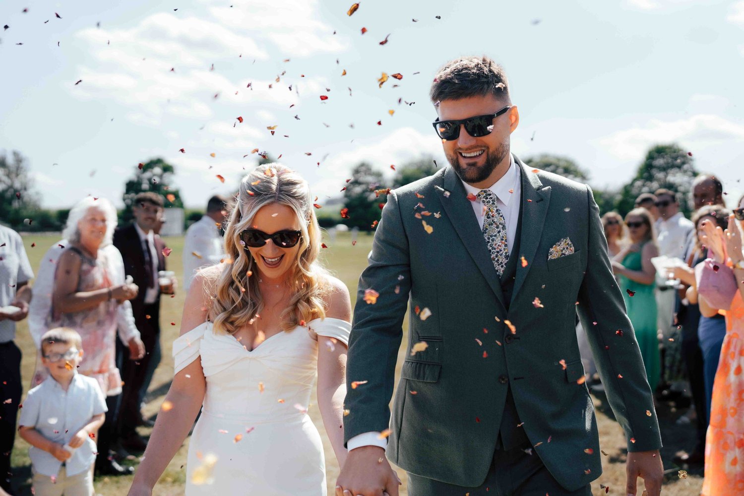 Candid bride and groom celebrated with thrown confetti by wedding guests at a Berkshire wedding venue