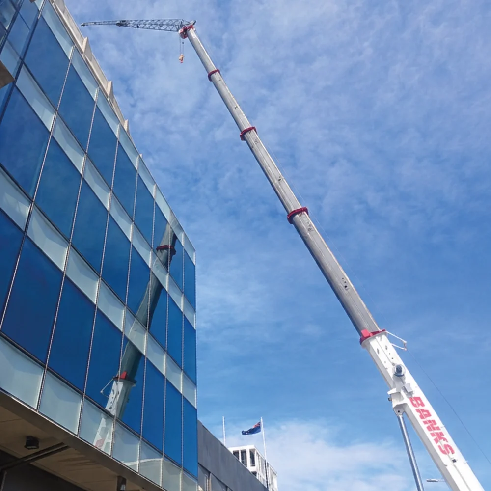 Banks Crane and Transport mobile crane carrying out high-level lifting beside a multi-storey building.