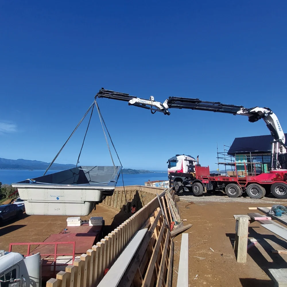 Banks Crane and Transport HIAB crane truck lifting a swimming pool into position at a residential property.